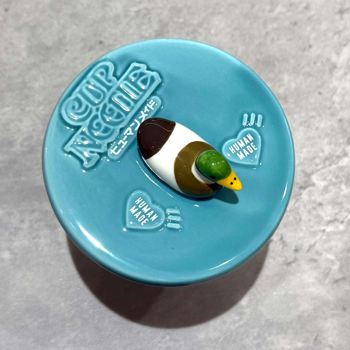 Human Made Lid Holder on a teal lid with a duck figure, designed for cup noodle bowls.