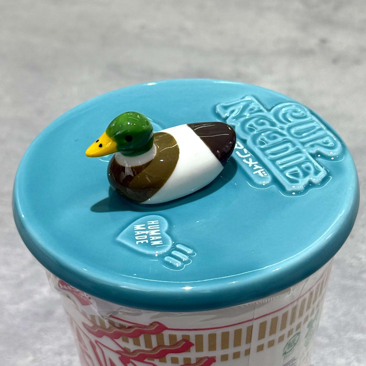 Human Made Lid Holder on a Cup Noodle cup lid, featuring a decorative duck design.