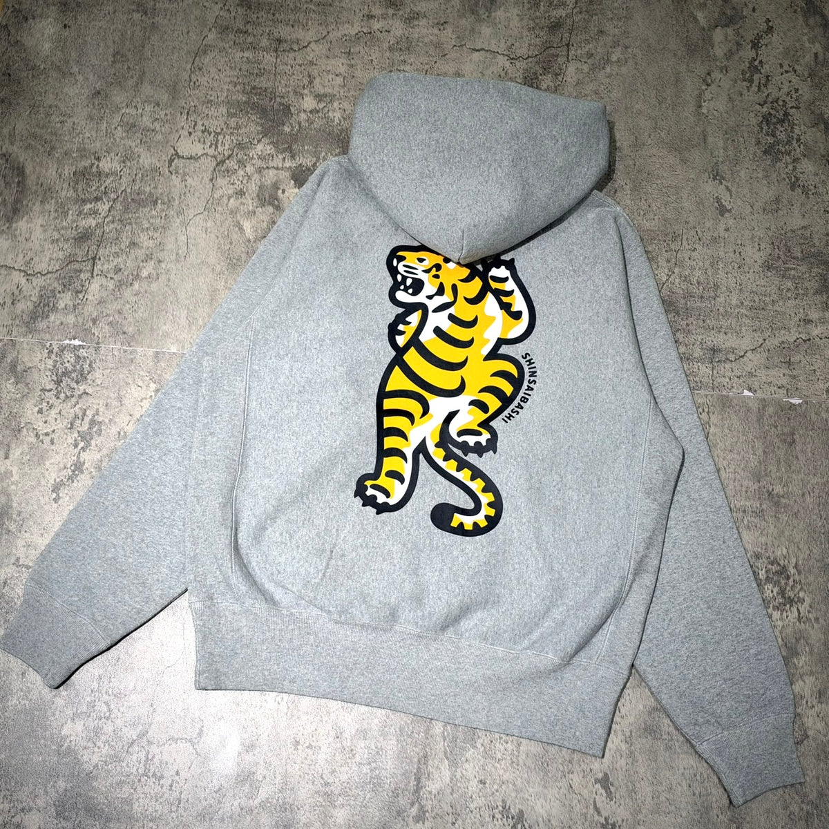Human Made Shinsaibashi Exclusive Tiger Heavyweight Hoodie featuring a bold tiger design on a gray backdrop.