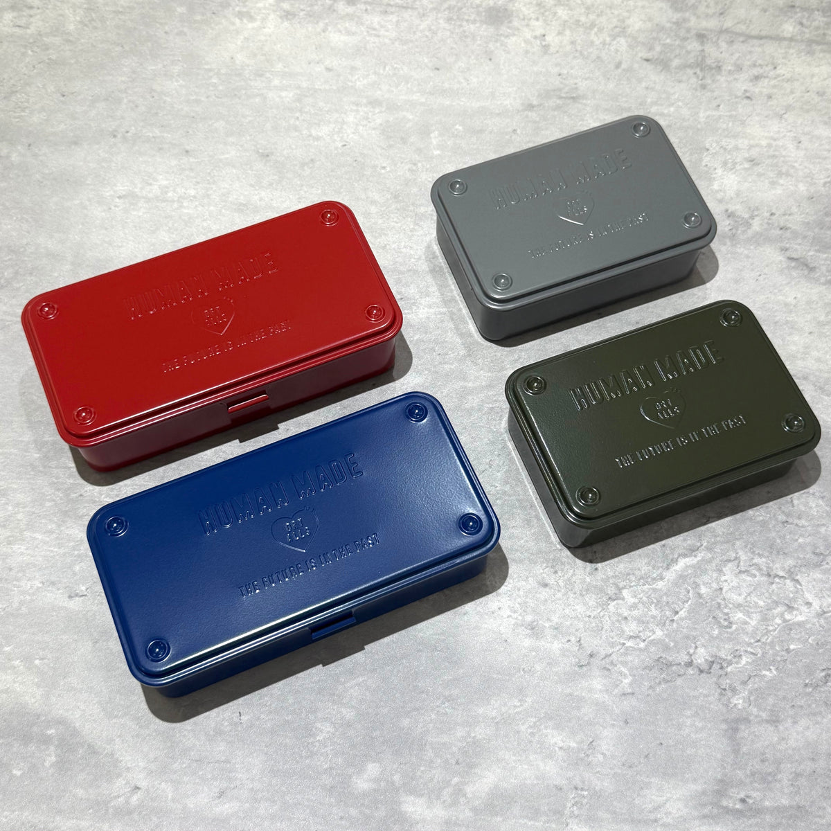 Image of Human Made Steel Tool Box in four colors: red, navy blue, grey, and olive green on a textured background.