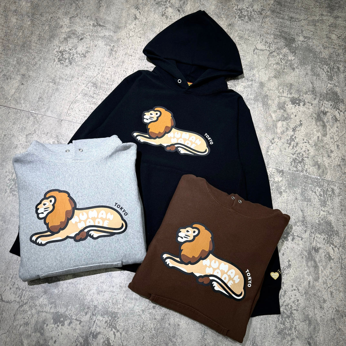 Human Made Tokyo Exclusive Lion Heavyweight Hoodie in gray, brown, and black with lion graphic design.