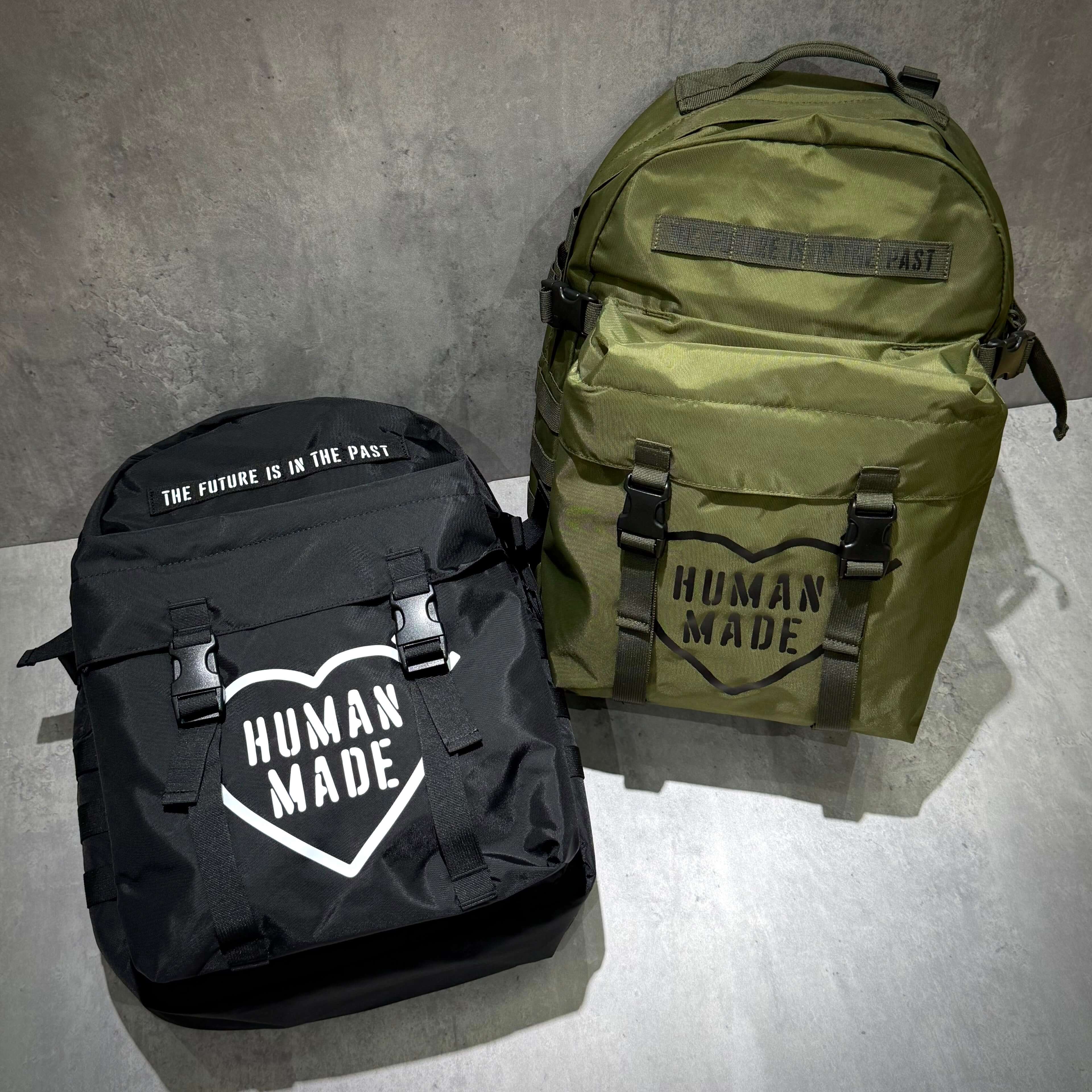 Human Made Military Backpack featuring a black and an olive green design, showcasing stylish logo and functional straps.