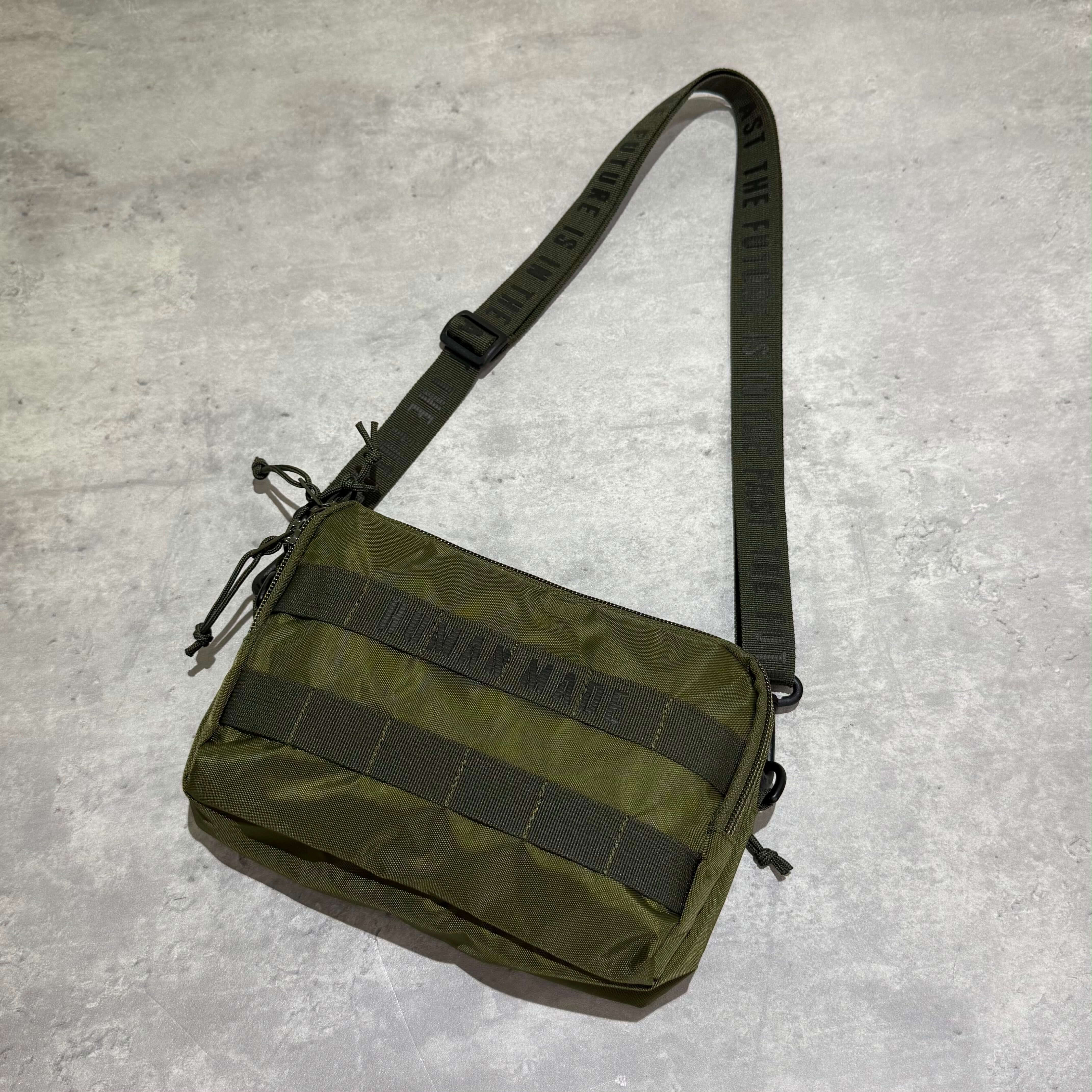 Human Made Military Pouch featuring adjustable strap and olive green design, perfect for outdoor and casual use.