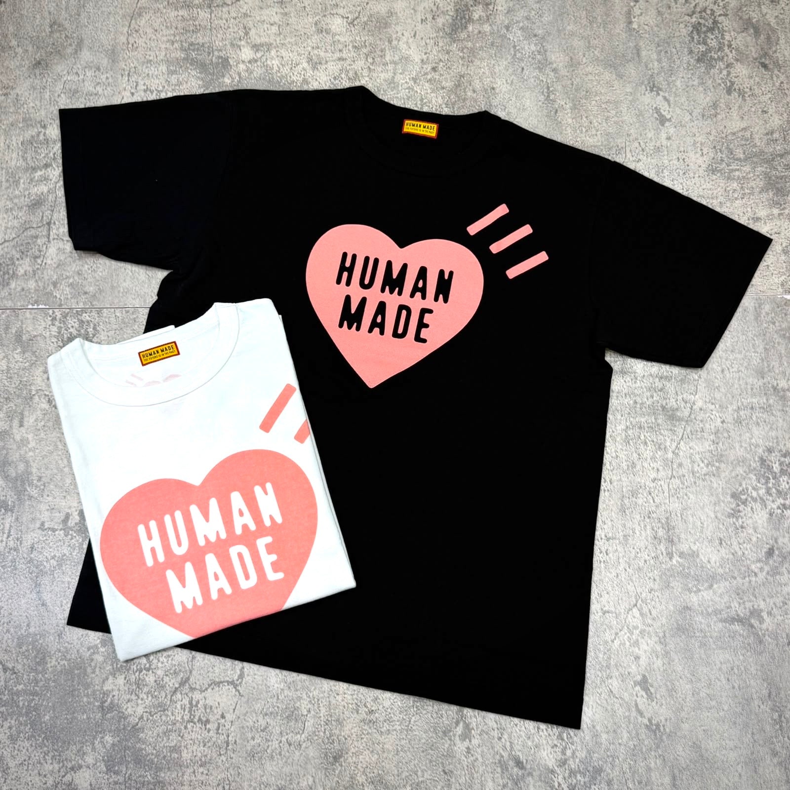 Human Made Seoul Exclusive Heart Logo Tee in black and white color options, featuring a heart logo and text.
