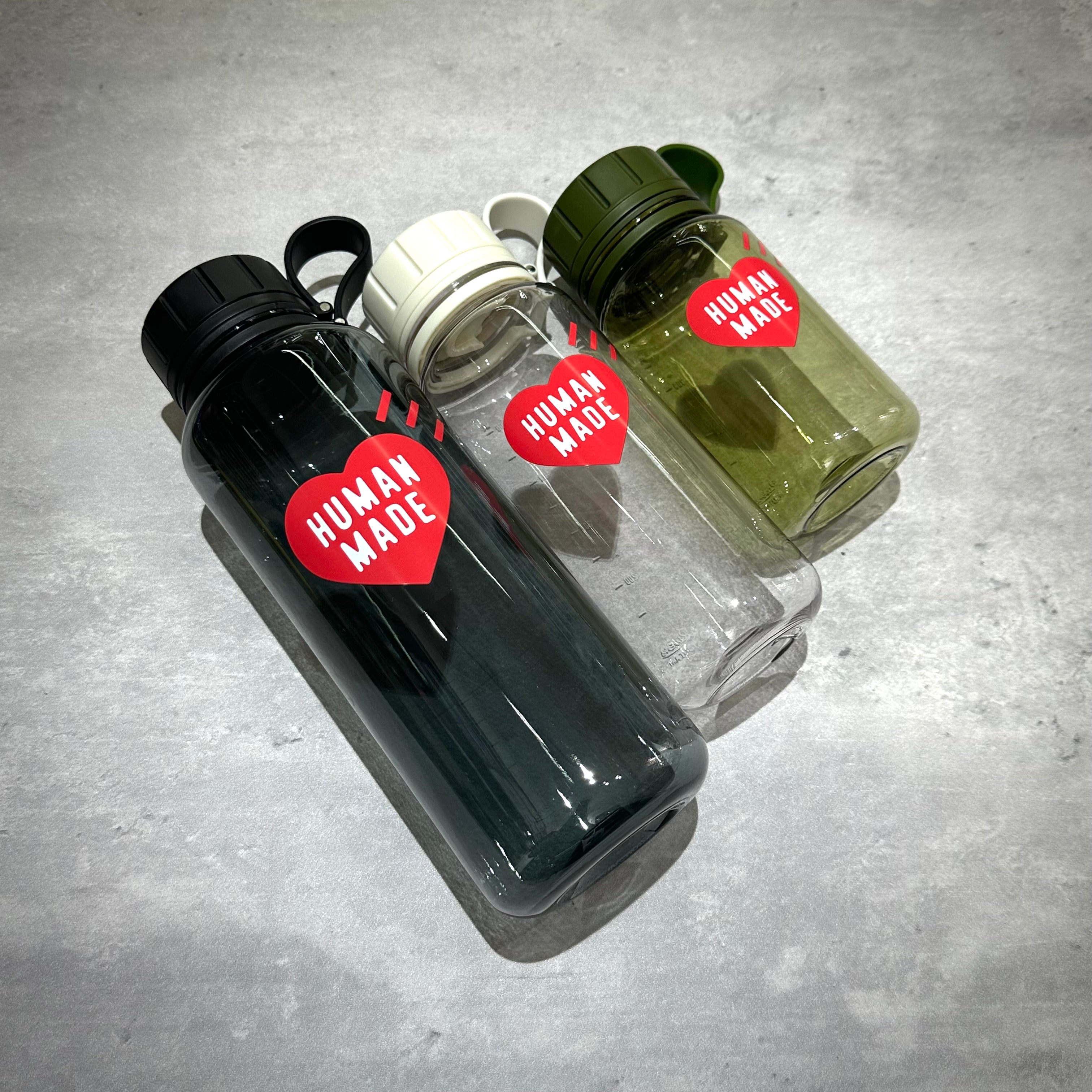 Three Human Made Water Bottles in different colors on a gray surface.