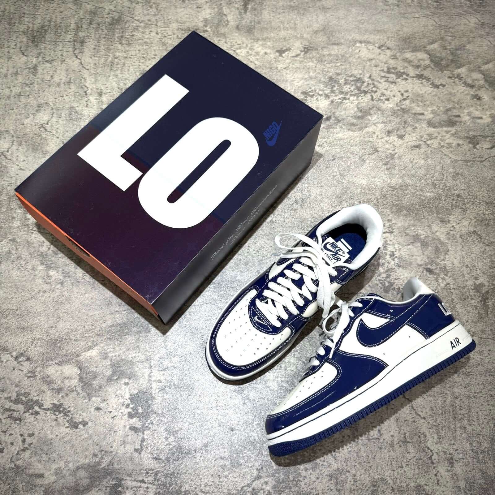 Nigo x Nike Air Force 1 LAST ORGY 2 sneakers with box, showcasing navy and white color scheme on a textured surface.