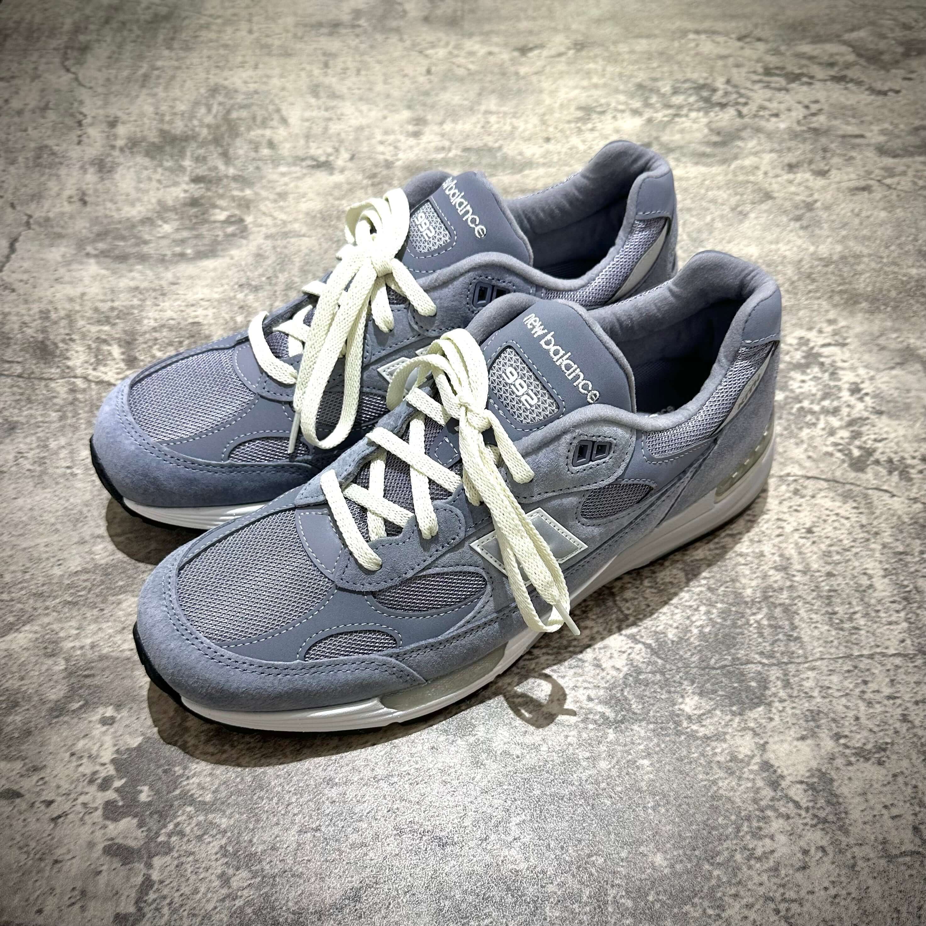 MiUSA Kith x New Balance 992 Argon sneakers in grey color with white laces on a textured surface.
