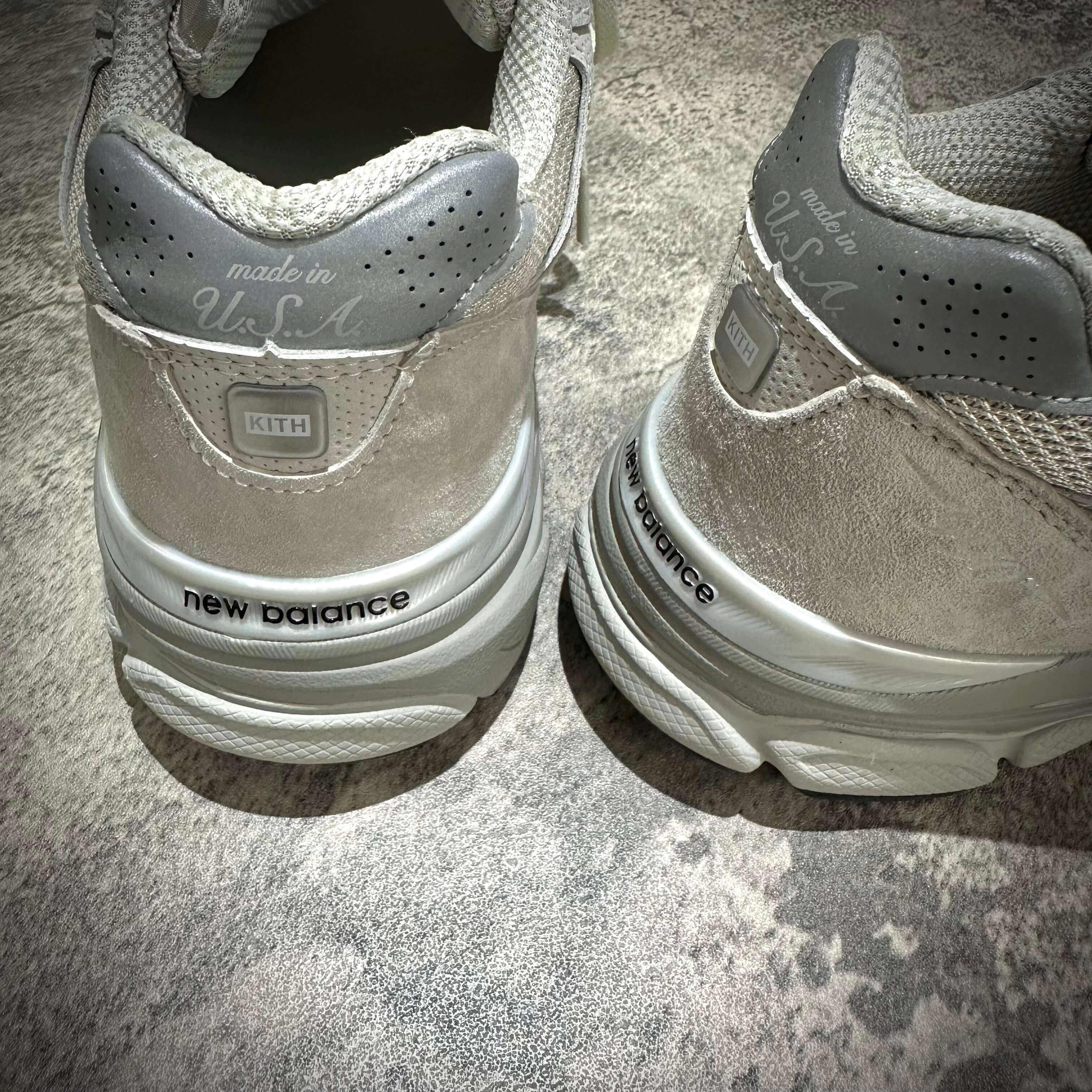 Detail view of the MiUSA Kith x New Balance 990v3 Hallow shoes showcasing branding and design elements.