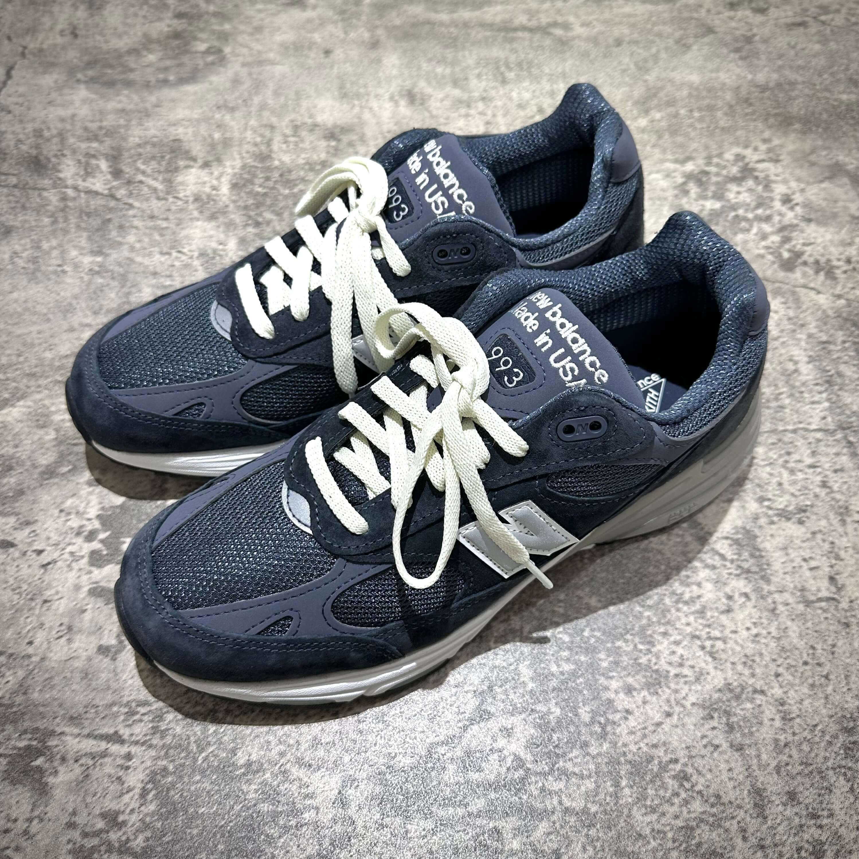 MiUSA Kith x New Balance 993 Asteroid shoes in dark blue with white laces on a textured surface.