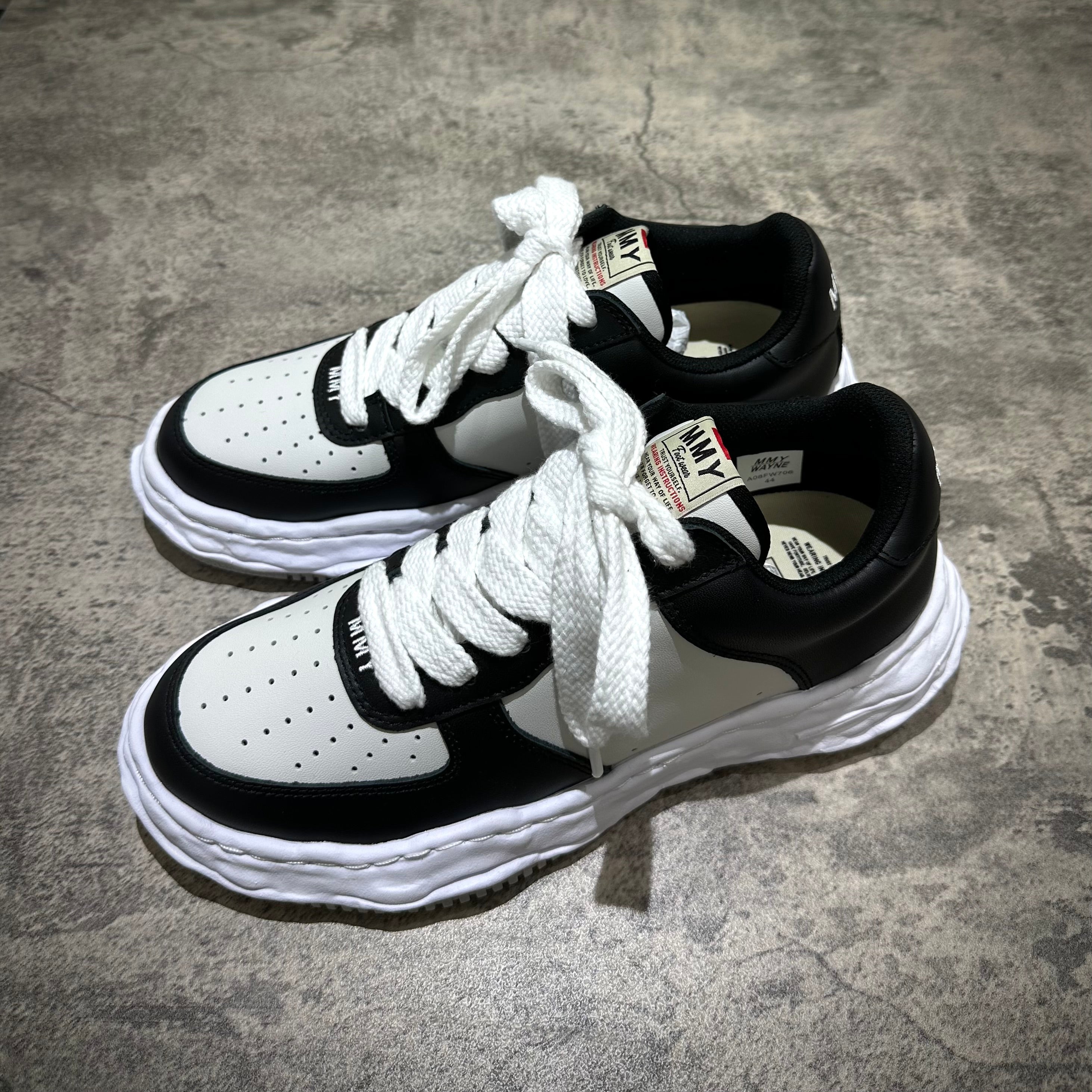 MMY WAYNE OG Leather sneaker in black and white with lace-up design on a gray surface.