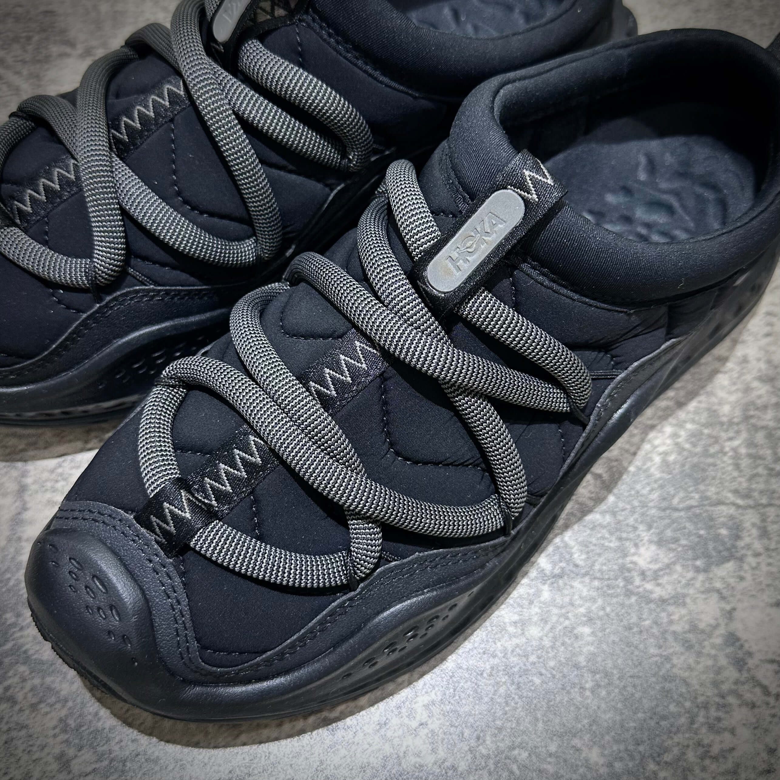 Hoka Ora Primo - Black shoes featuring unique lacing system and sleek design, perfect for casual wear.