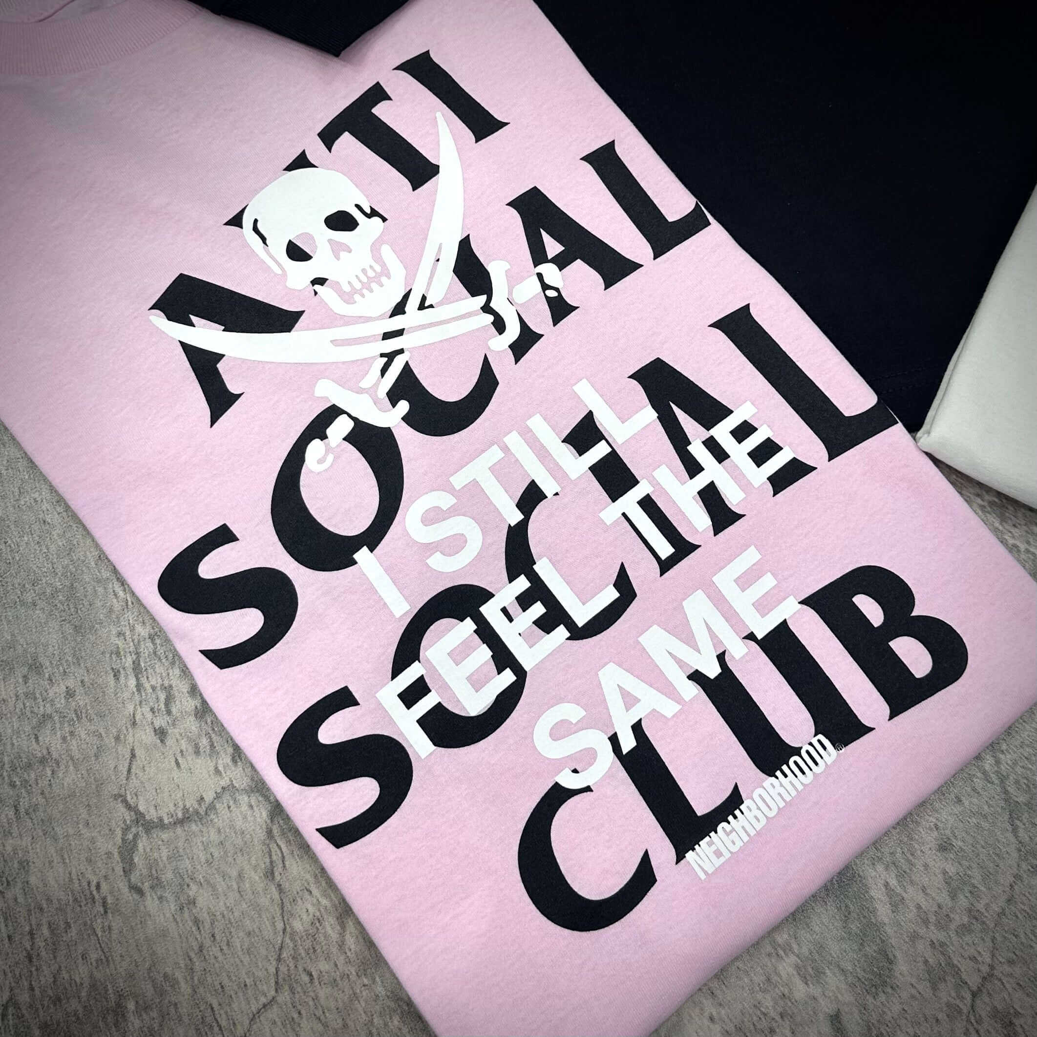 Image of ASSC x Neighborhood Black Jack L/S Tee in pink, featuring bold text and graphic design.