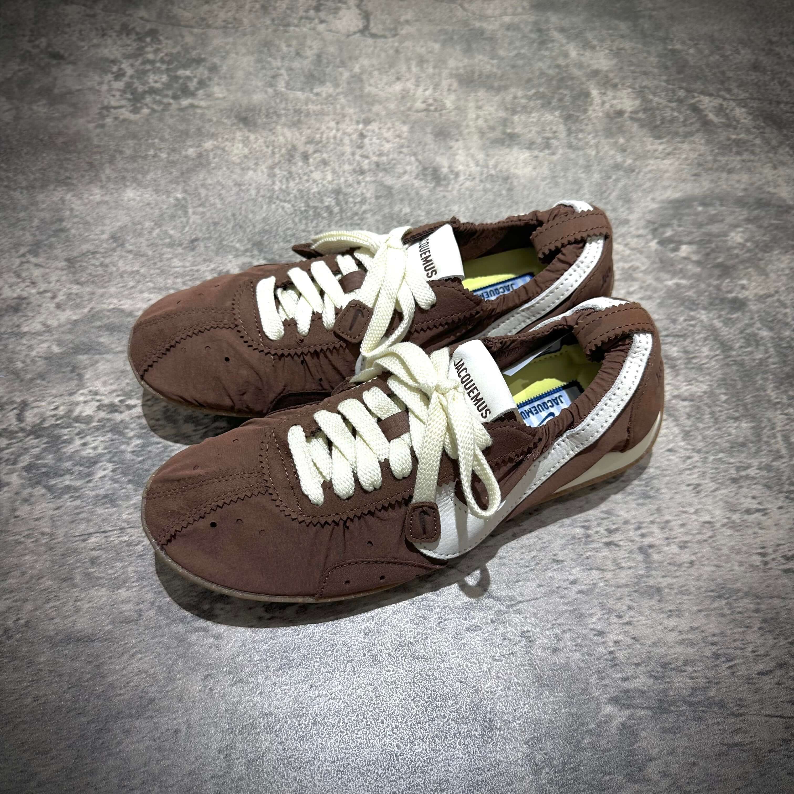 Jacquemus x Nike Moon Shoe SP - Brown pair of sneakers with white laces on a textured surface.