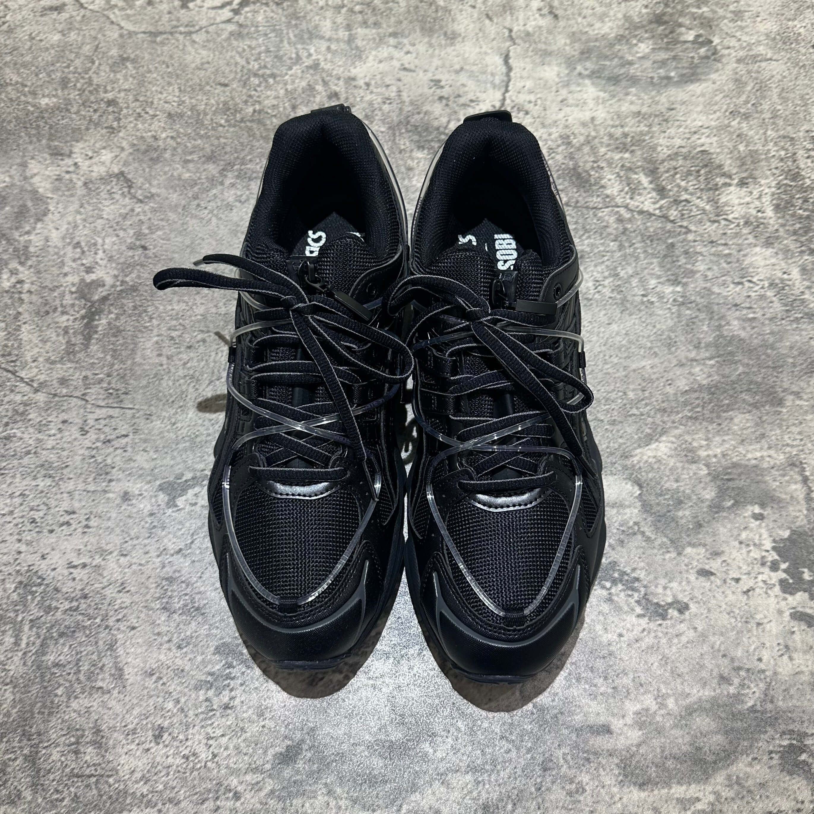 Yoasobi x Asics Gel Kinetic Fluent Y - Black sneakers top view with black mesh and laces on a textured surface.