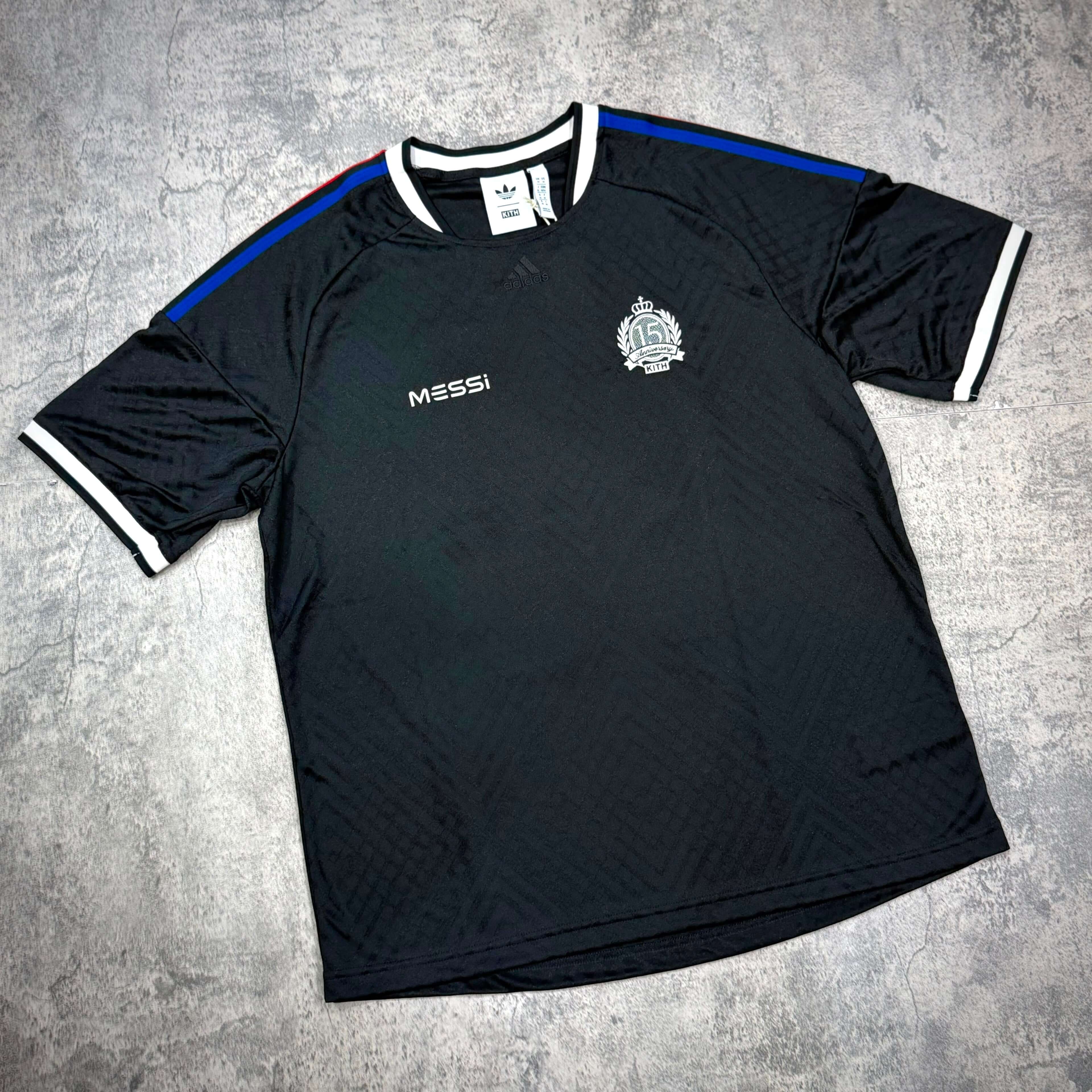 KITH x MESSI for adidas Football Jersey - Black displayed on a flat surface, featuring intricate detailing and brand logos.