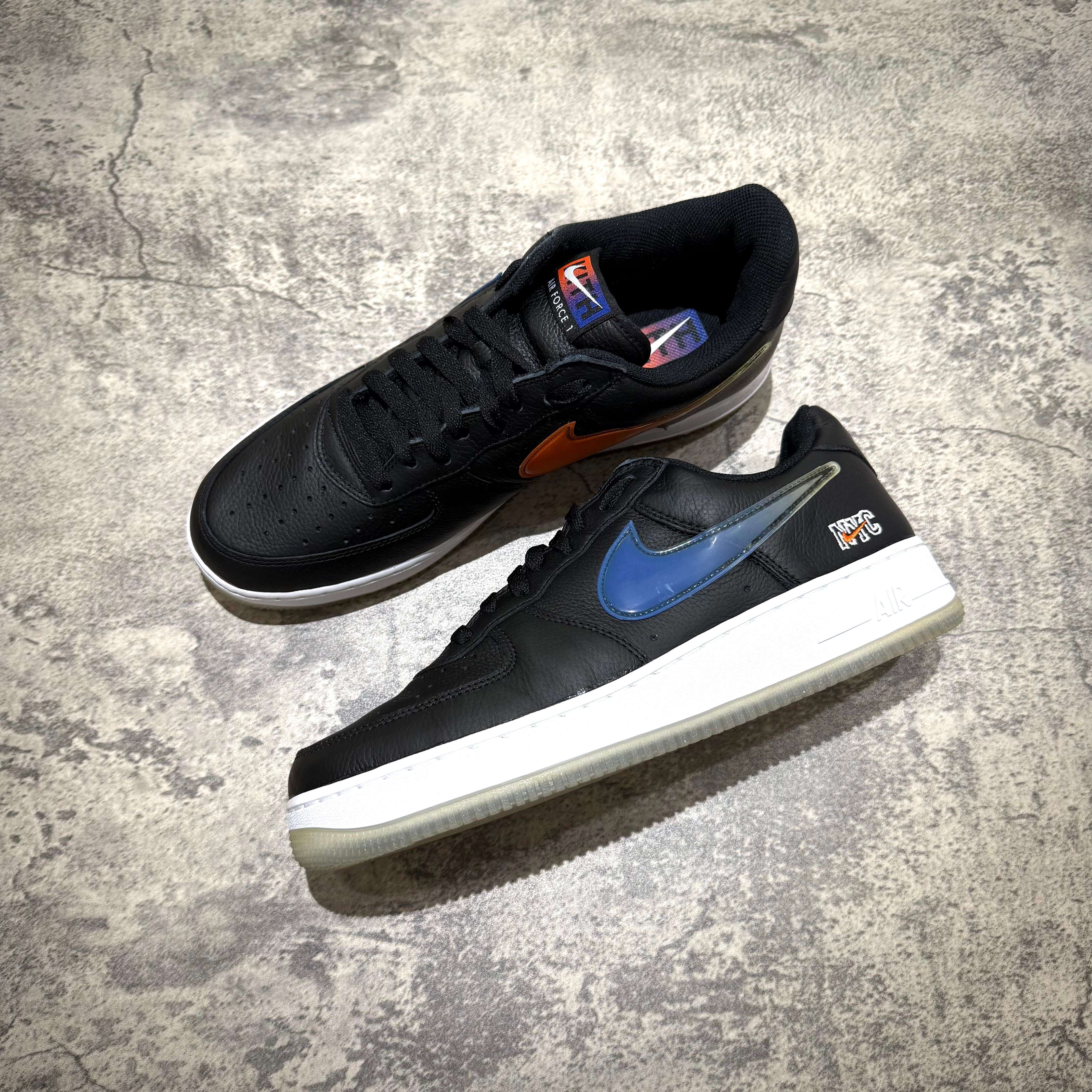 KITH x Nike Air Force 1 Low Knicks sneakers with black upper and blue swoosh, stylish design, and authentic branding.