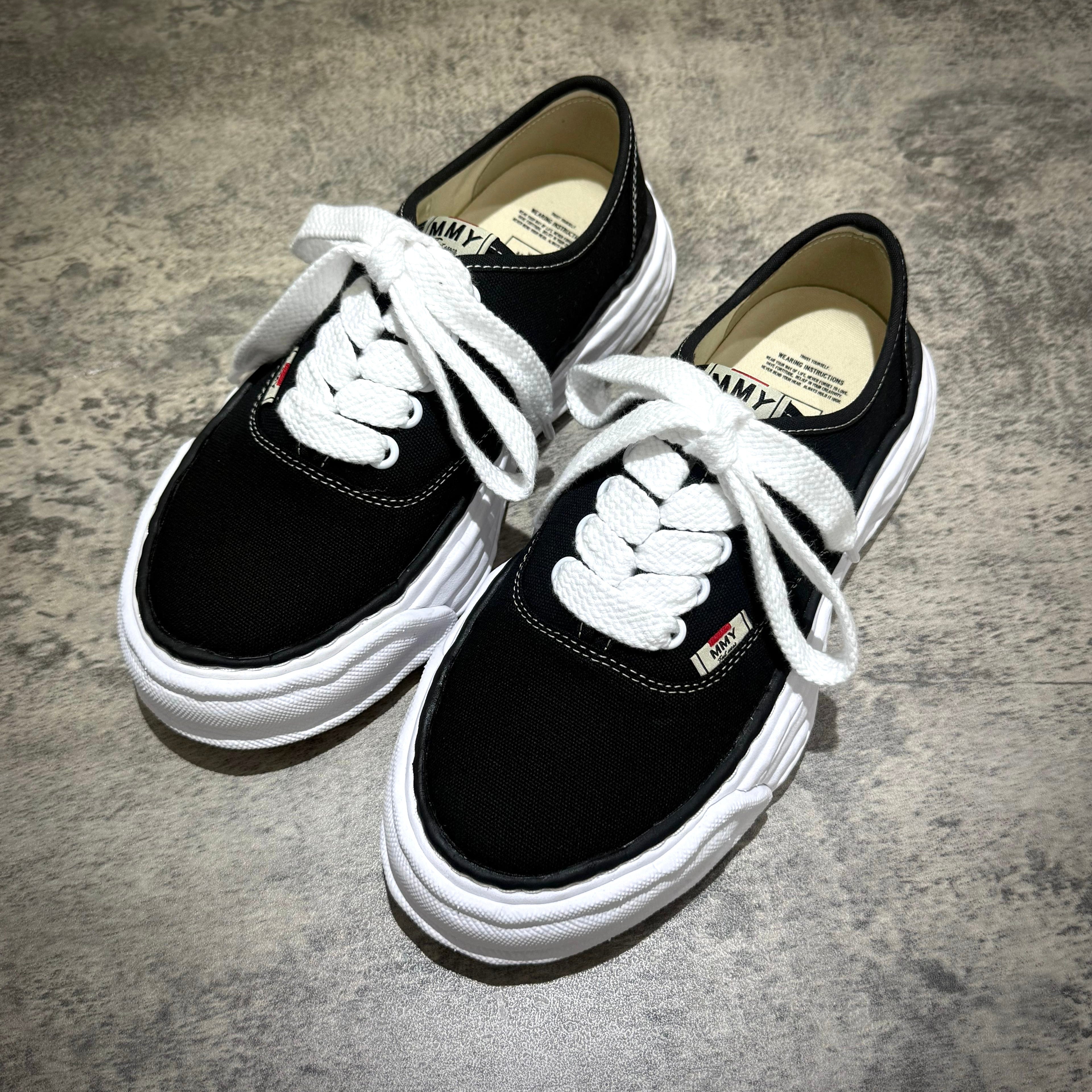 MMY Baker26 Canvas Low - Black shoes with white laces on a textured surface.