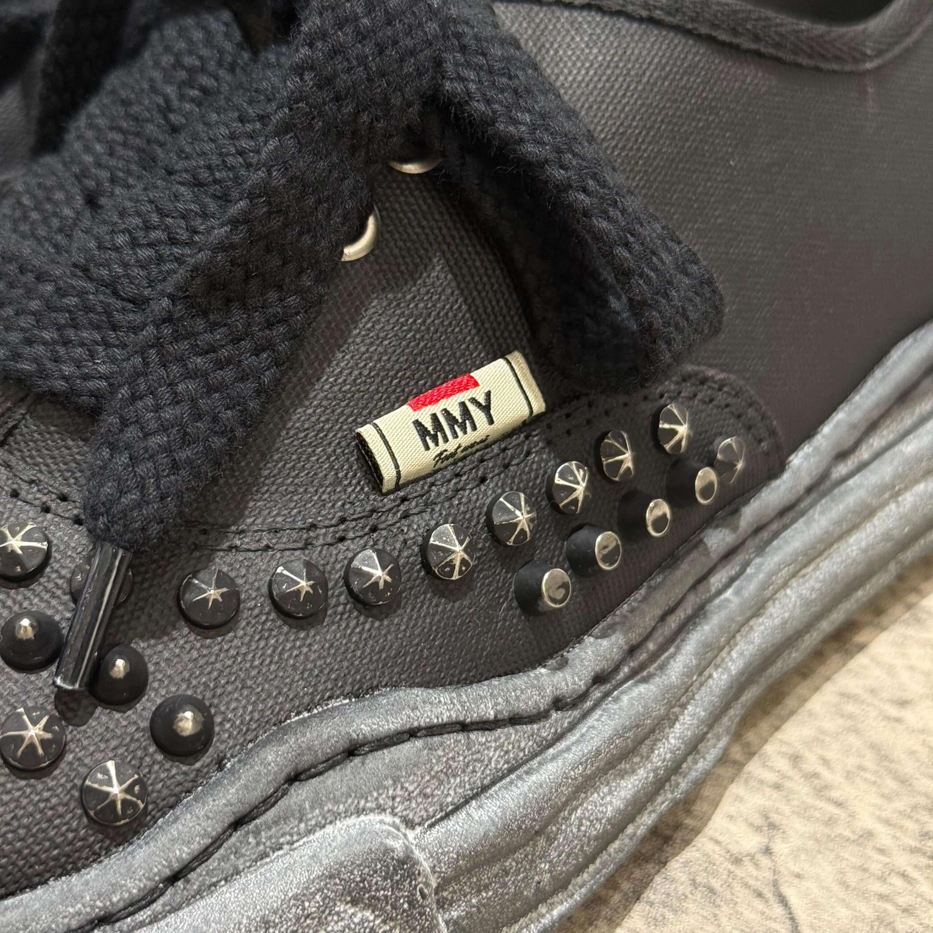 Close-up of MMY Baker studded canvas low shoe showcasing black studs and the MMY label.