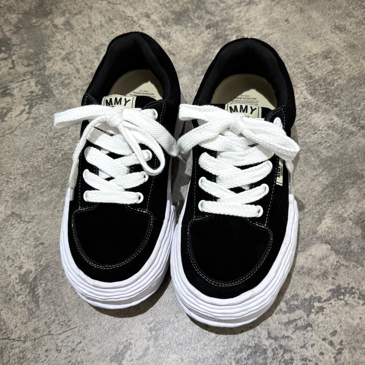 MMY Oliver Suede Low - Black sneakers with white laces and textured sole on a grey background.