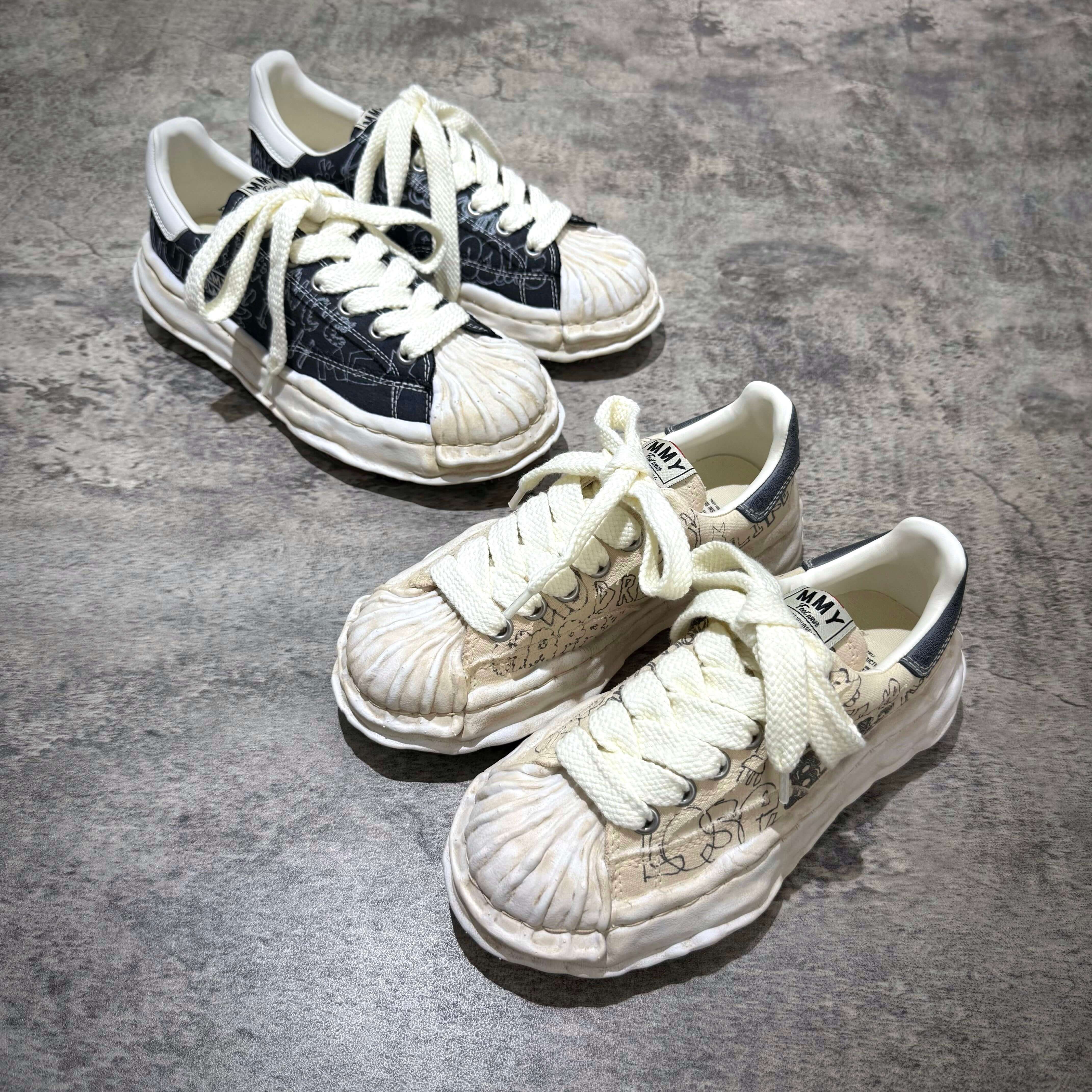 MMY BLAKEY Graffiti Printed Canvas Low sneakers in black and beige on a gray surface.