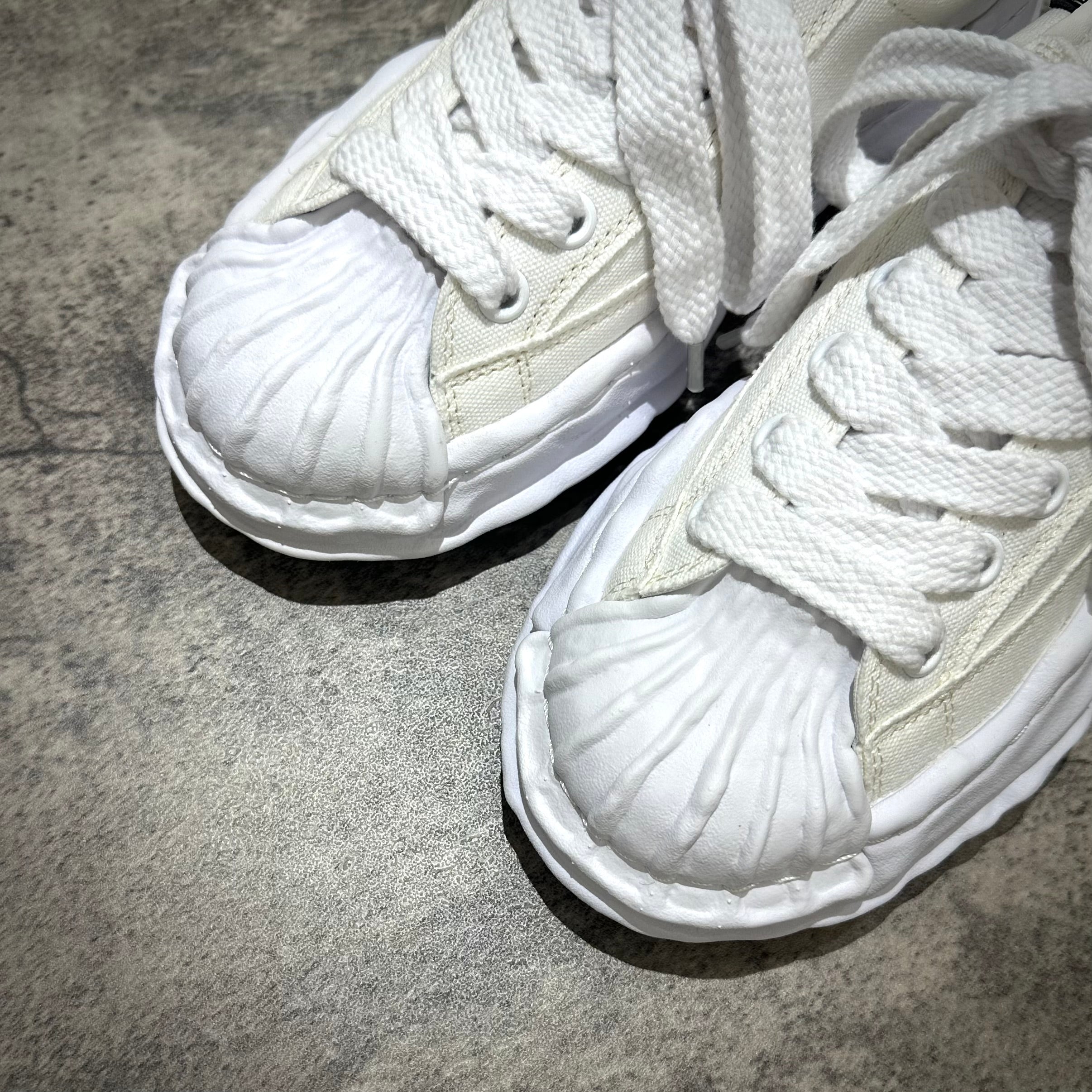 MMY BLAKEY OG Canvas - White sneaker close-up, showcasing white laces and unique shell toe design.