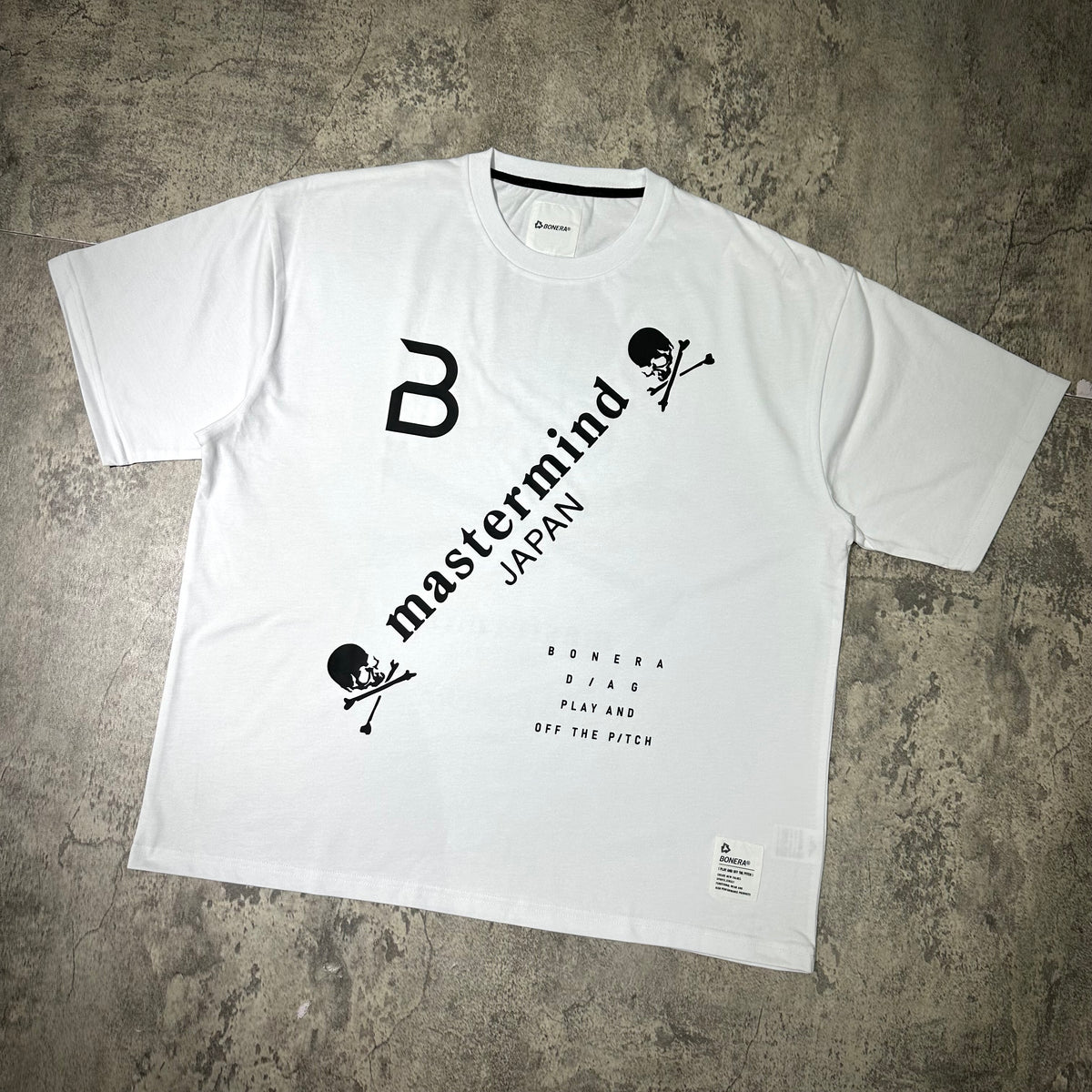 Mastermind Japan x Bonera Tee displayed on a textured surface, featuring bold graphics and a casual fit.