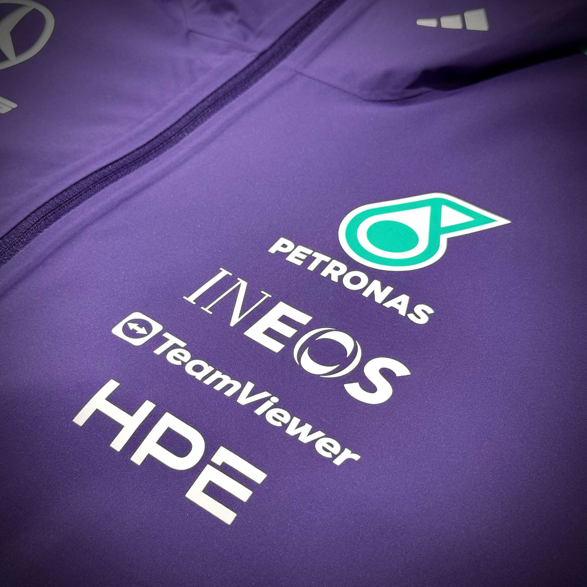 Mercedes-AMG Petronas Formula 1 Team Vanda Bloom Rain Jacket logo details featuring Petronas, INEOS, TeamViewer, and HPE branding.