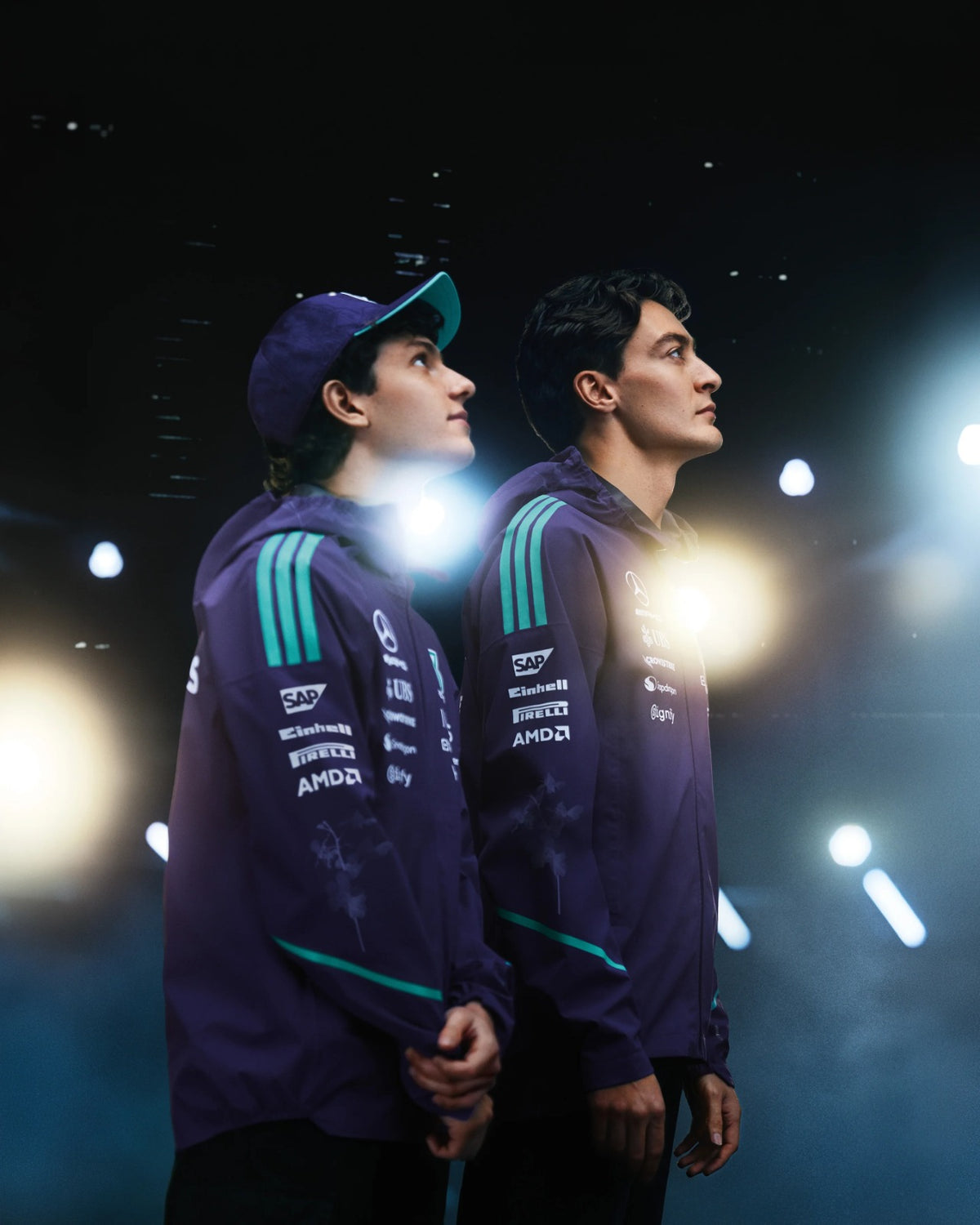 Mercedes-AMG Petronas Formula 1 Team Vanda Bloom Rain Jacket HZ9485 worn by two drivers under stage lights.