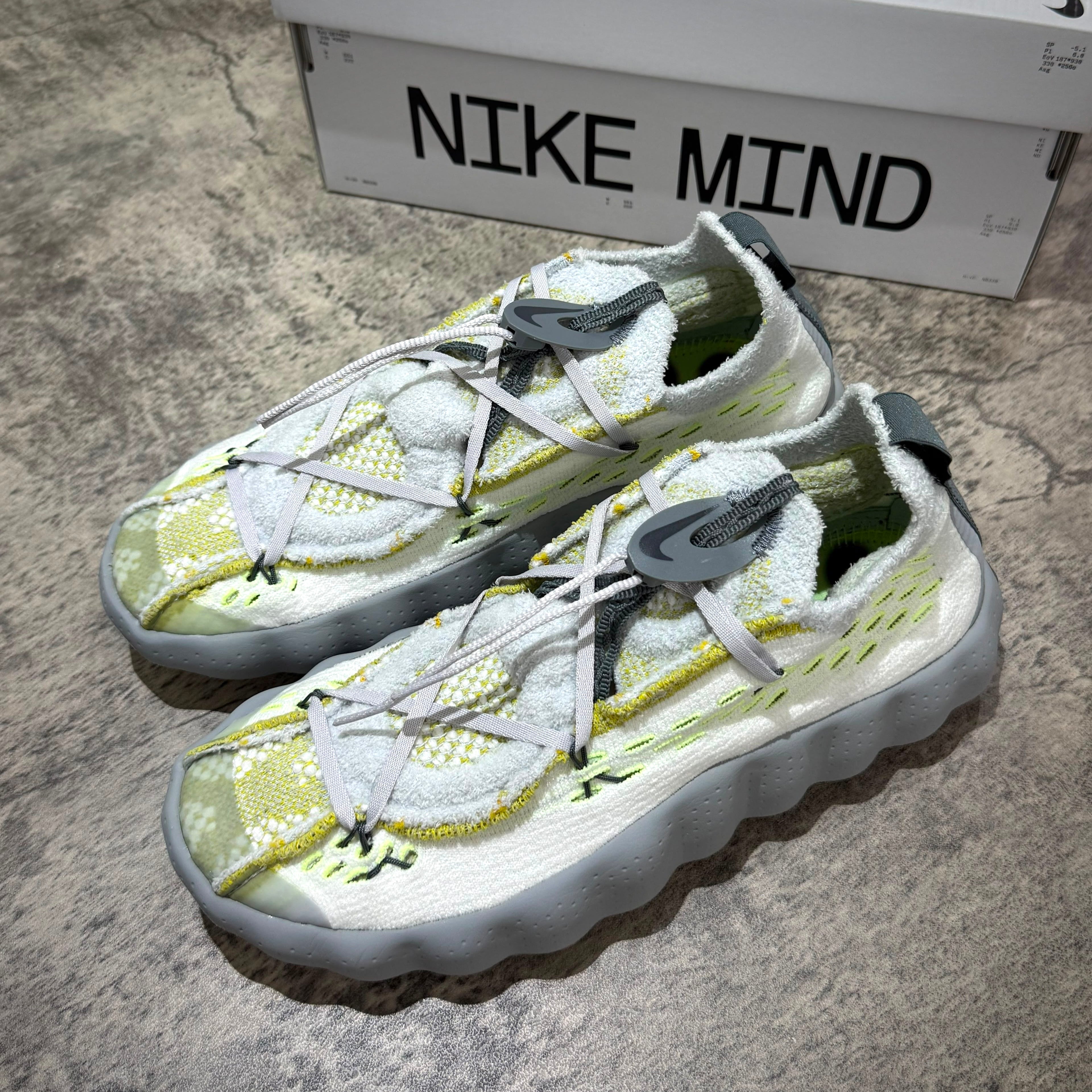 Nike Mind 002 Flyknit - Wolf Grey shoes with a vibrant yellow and white design, showcasing the unique Flyknit texture.