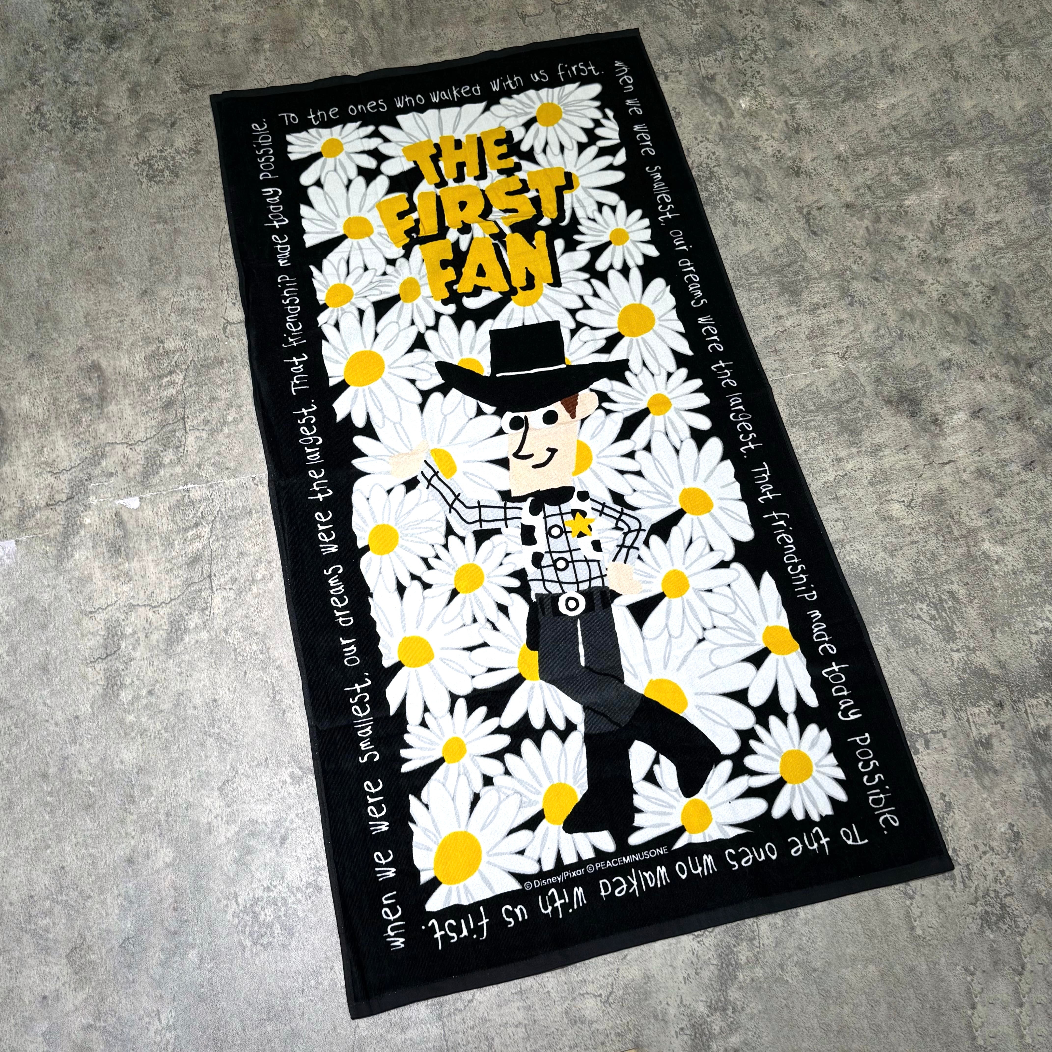 PEACEMINUSONE x Toy Story The First Fan - Beach Towel featuring a graphic design with flowers and character.