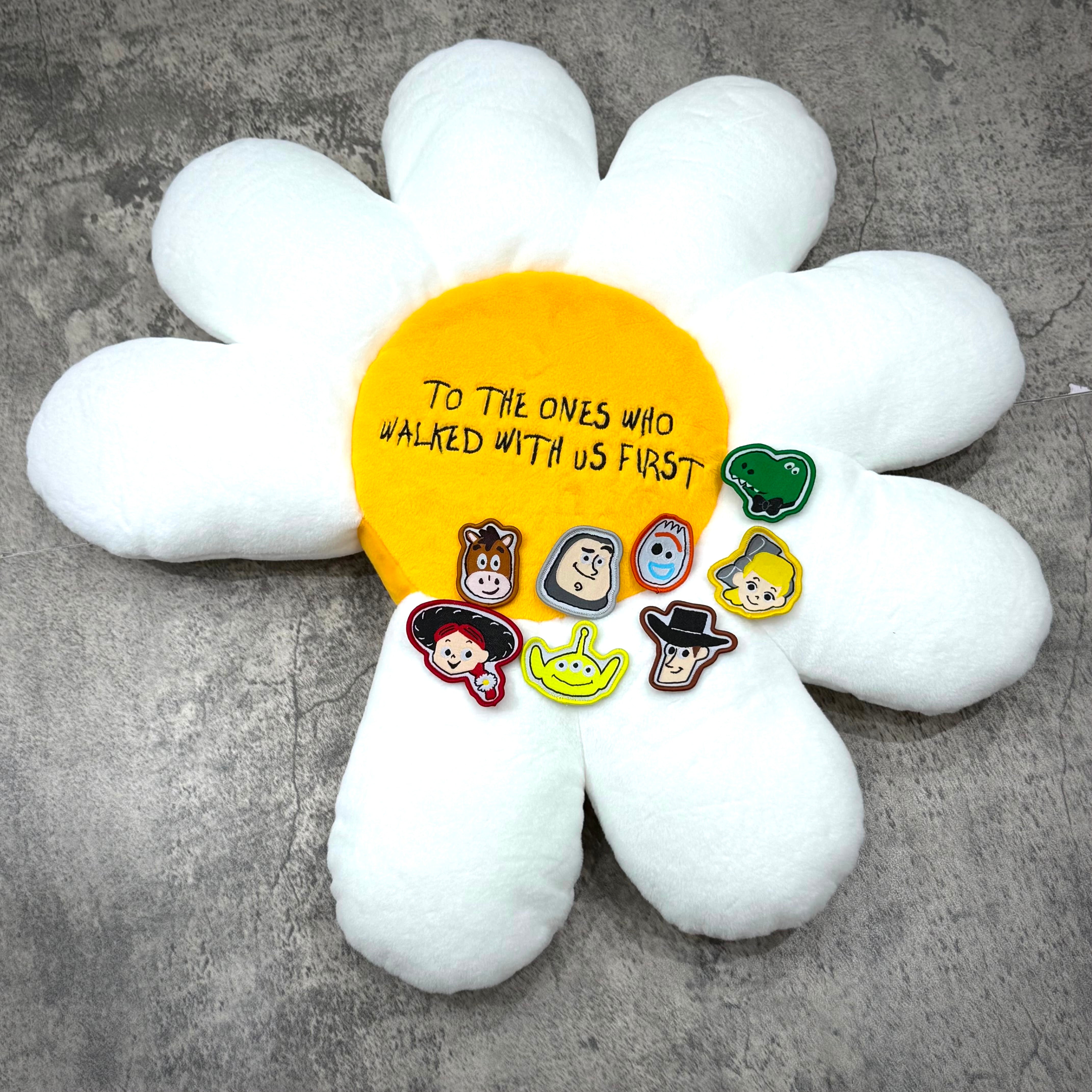 PEACEMINUSONE x Toy Story The First Fan - Daisy Cushion featuring a daisy design with character badges.