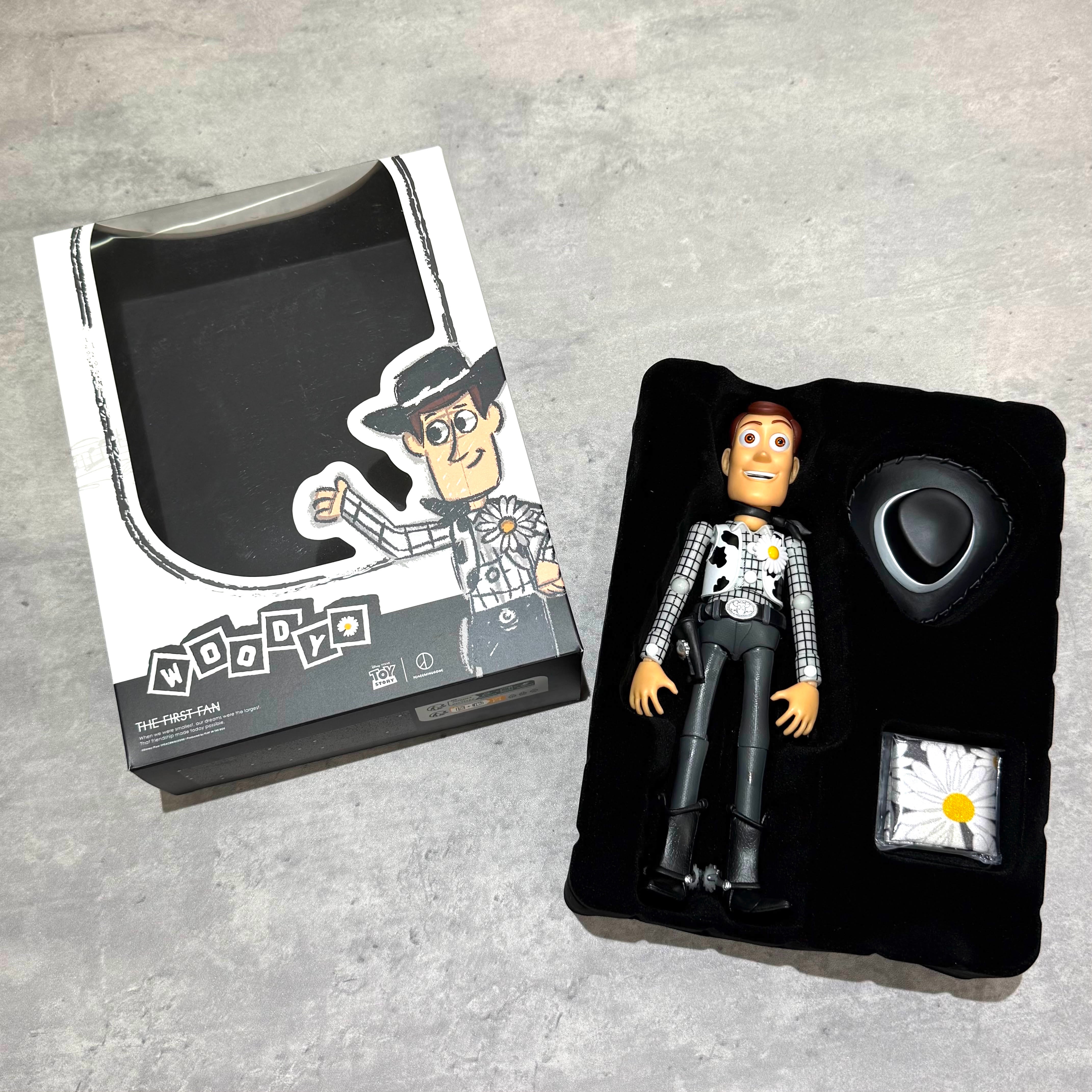 PEACEMINUSONE x Toy Story The First Fan - Action Figure Woody in packaging on a gray surface.