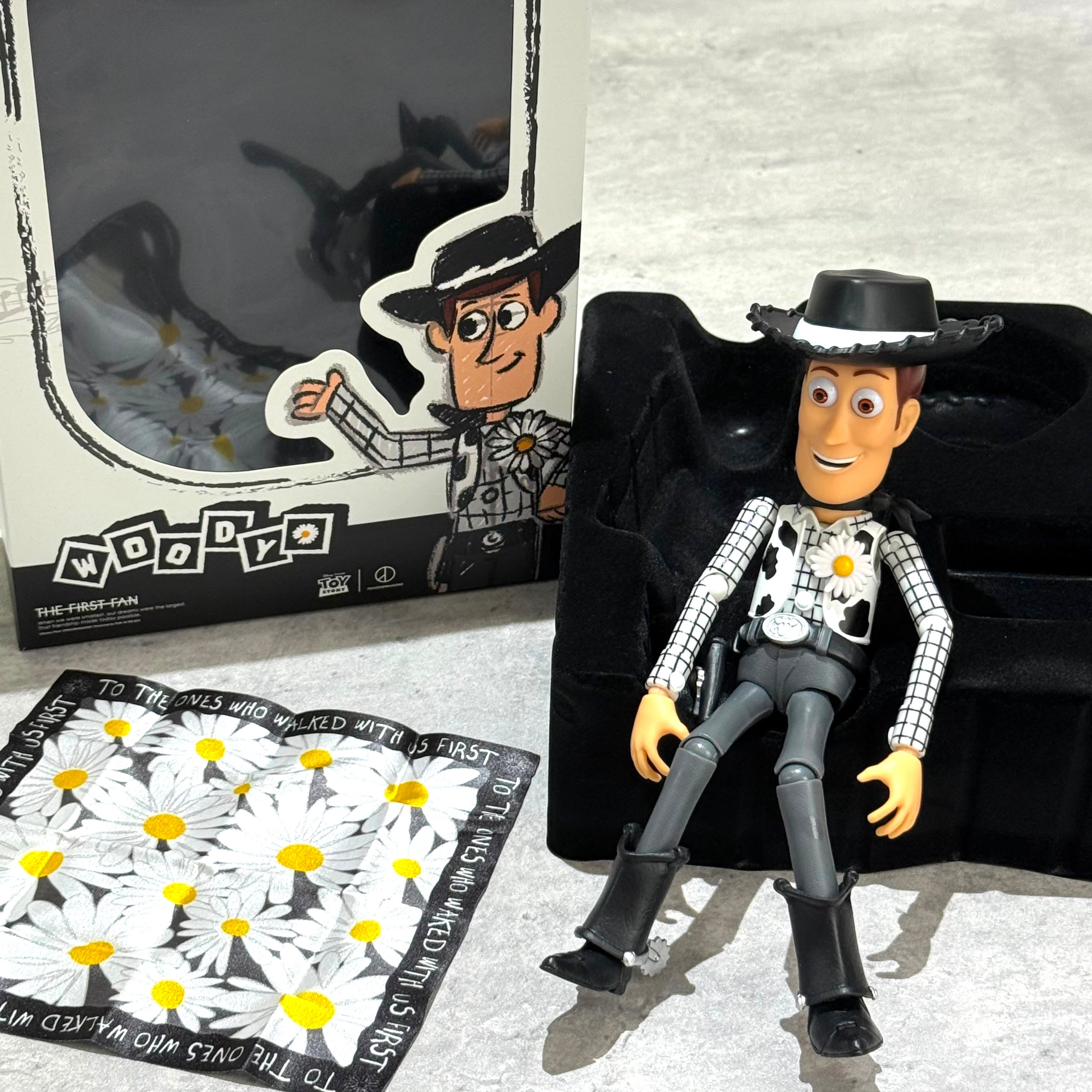 PEACEMINUSONE x Toy Story The First Fan - Action Figure Woody with box and daisy-themed cloth.