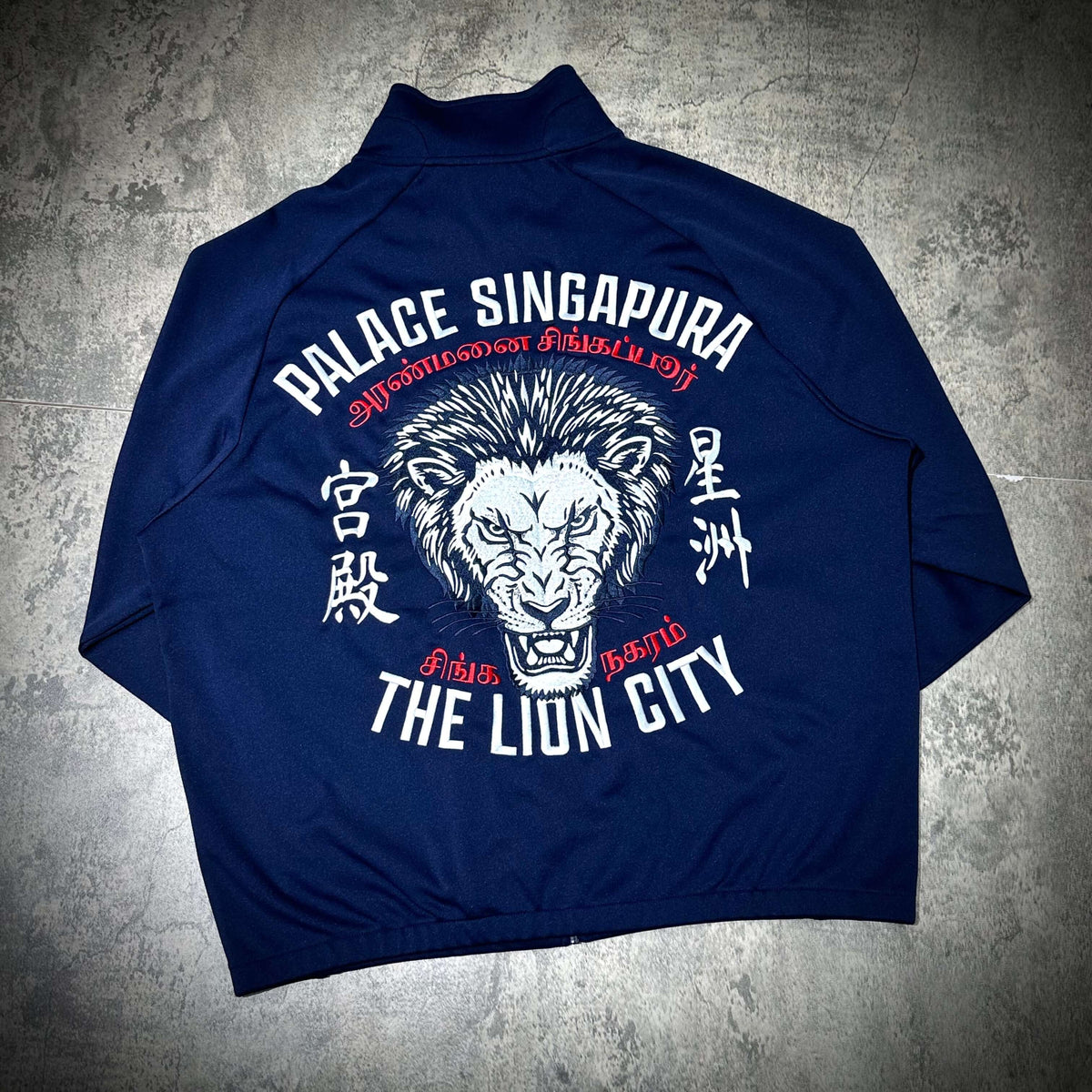 Palace Singapore Jacket featuring a lion graphic and text design on a navy blue background