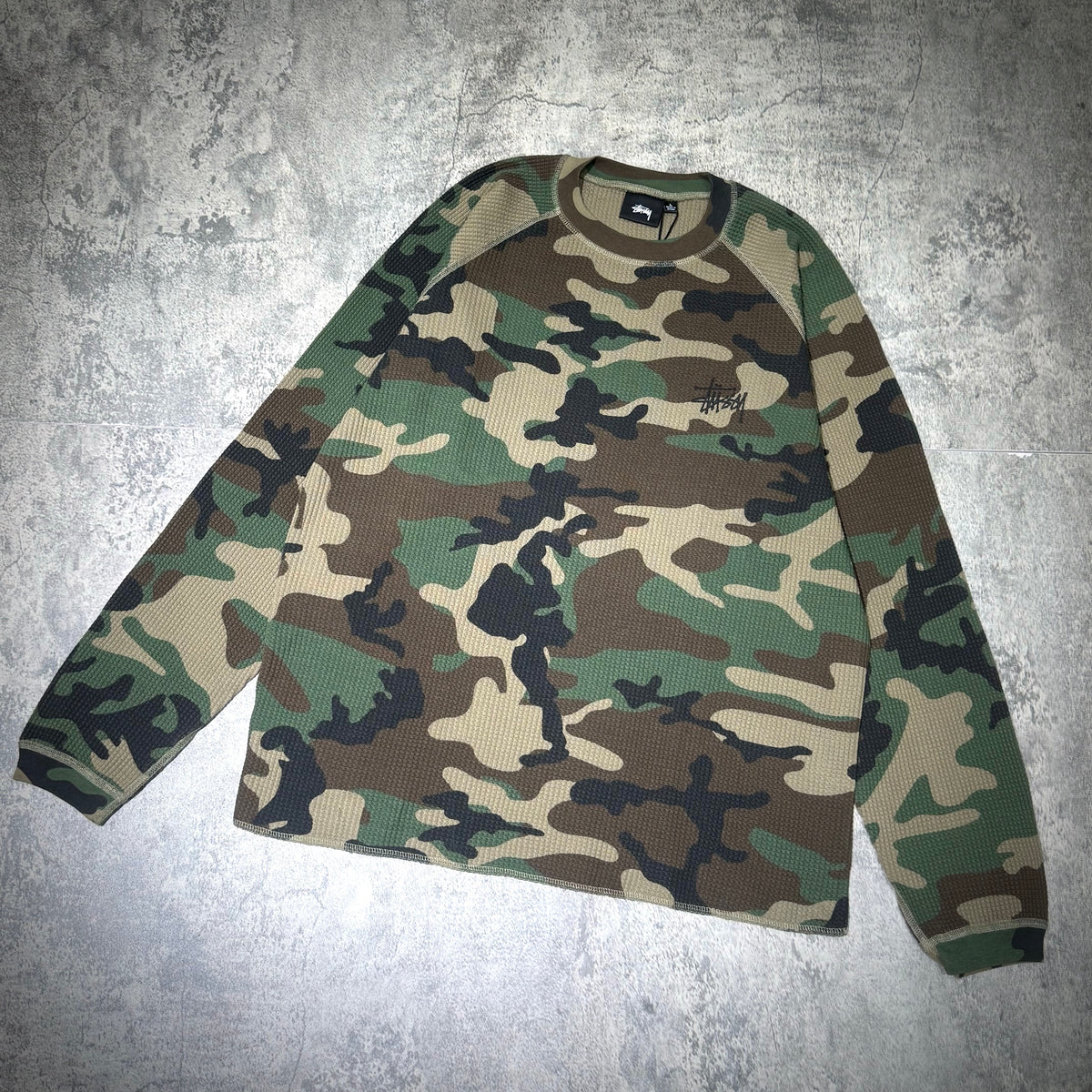 Stussy Basic Raglan Thermal LS Crew FW26 in a camouflage pattern, featuring long sleeves and a comfortable fit.