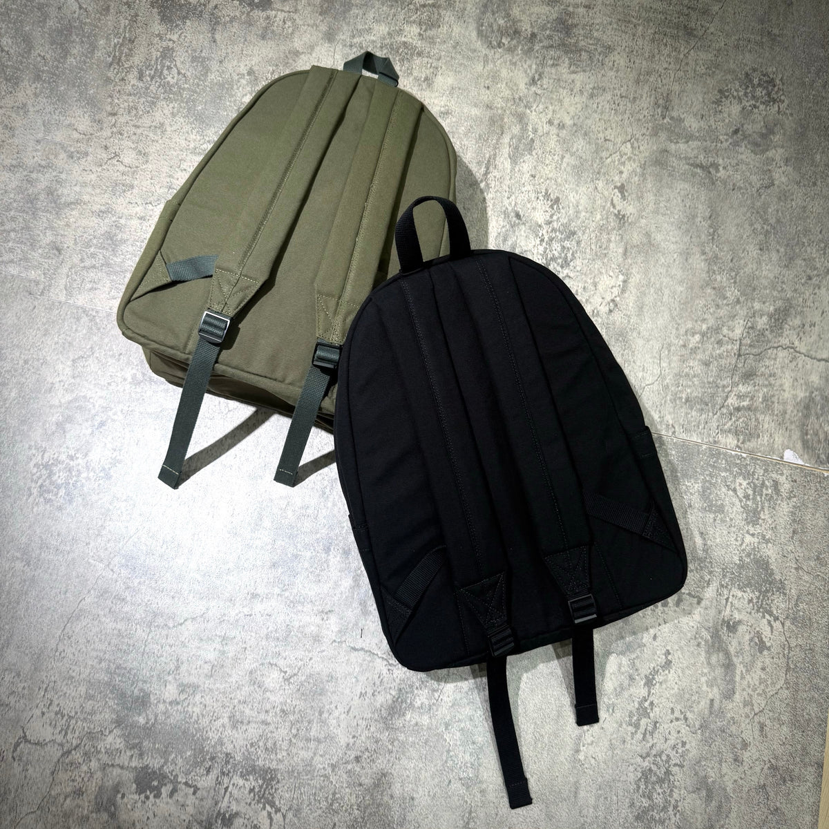 Stussy Canvas Backpack in olive green and black, showcasing the back view with padded straps and a sleek design.