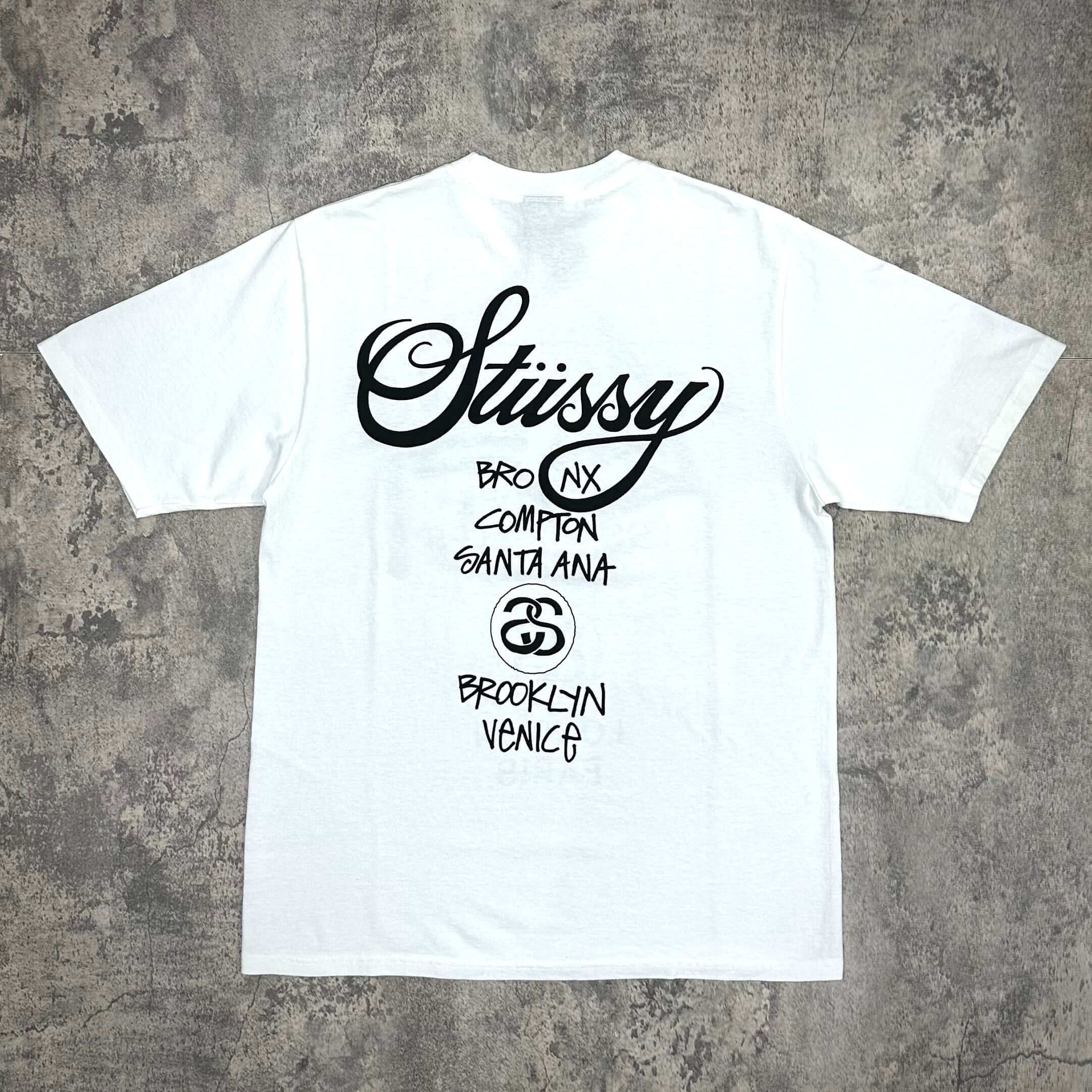 現貨 Stussy World Tour Tee - Navy / Black / White 後背圖樣，顯示 Stussy 標誌及城市名稱