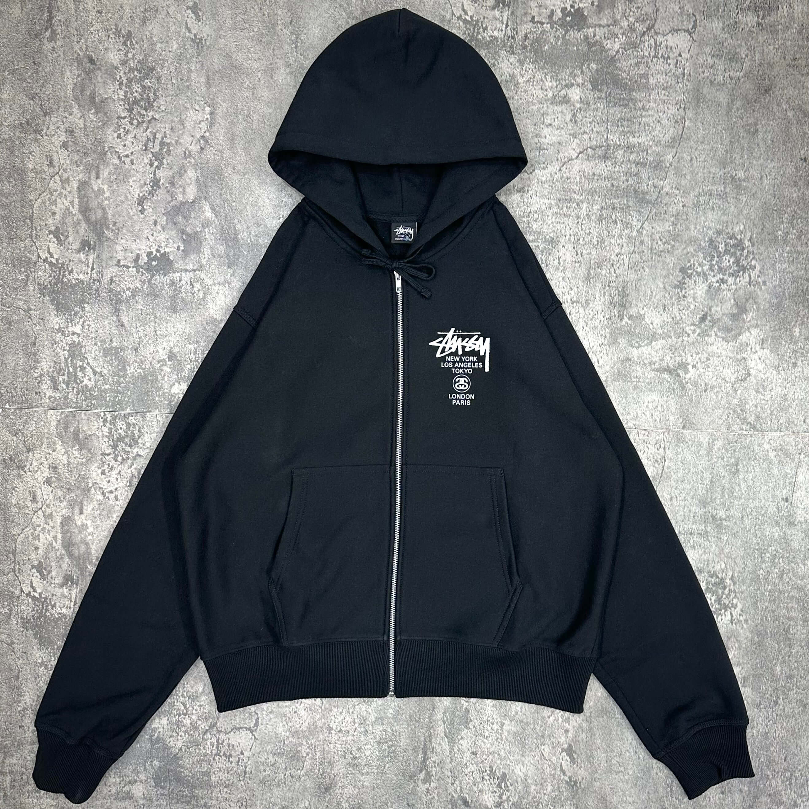現貨 Stussy World Tour Zip Hoodie - Navy / Black / Grey，黑色拉鍊衛衣，前方印有Stussy標誌，適合休閒穿搭。