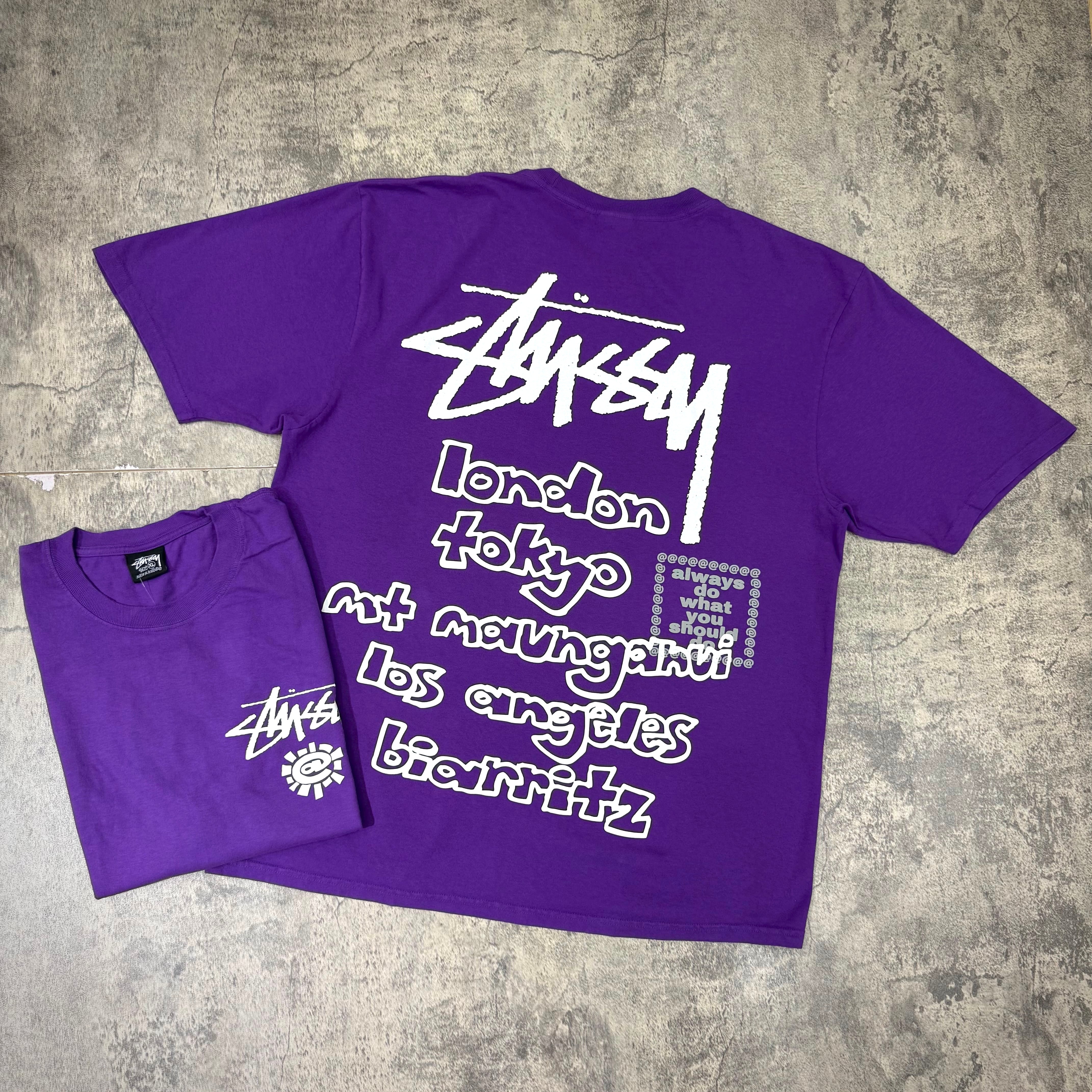 Stussy x Always Do What You Should Do World Tour Tee in purple, featuring city names on the back.