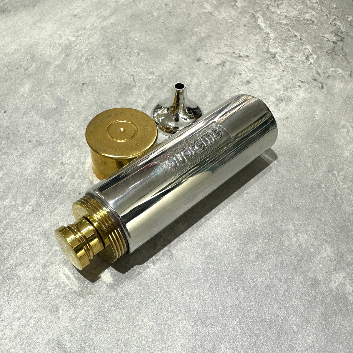 Supreme English Pewter Company Bullet Flask with lid and filler spout on a textured surface.