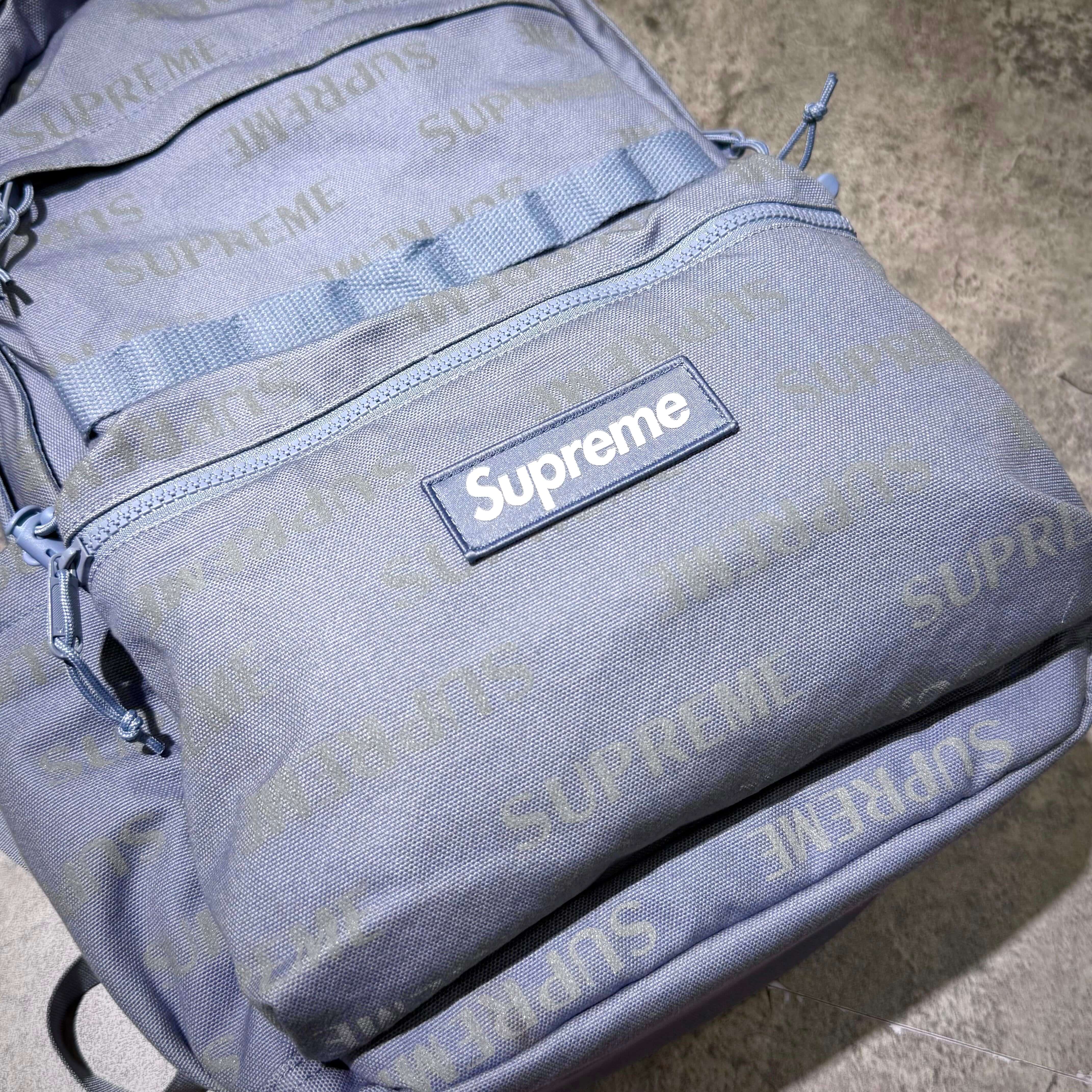 Supreme FW26 Backpack with logo design on textured fabric in gray color.