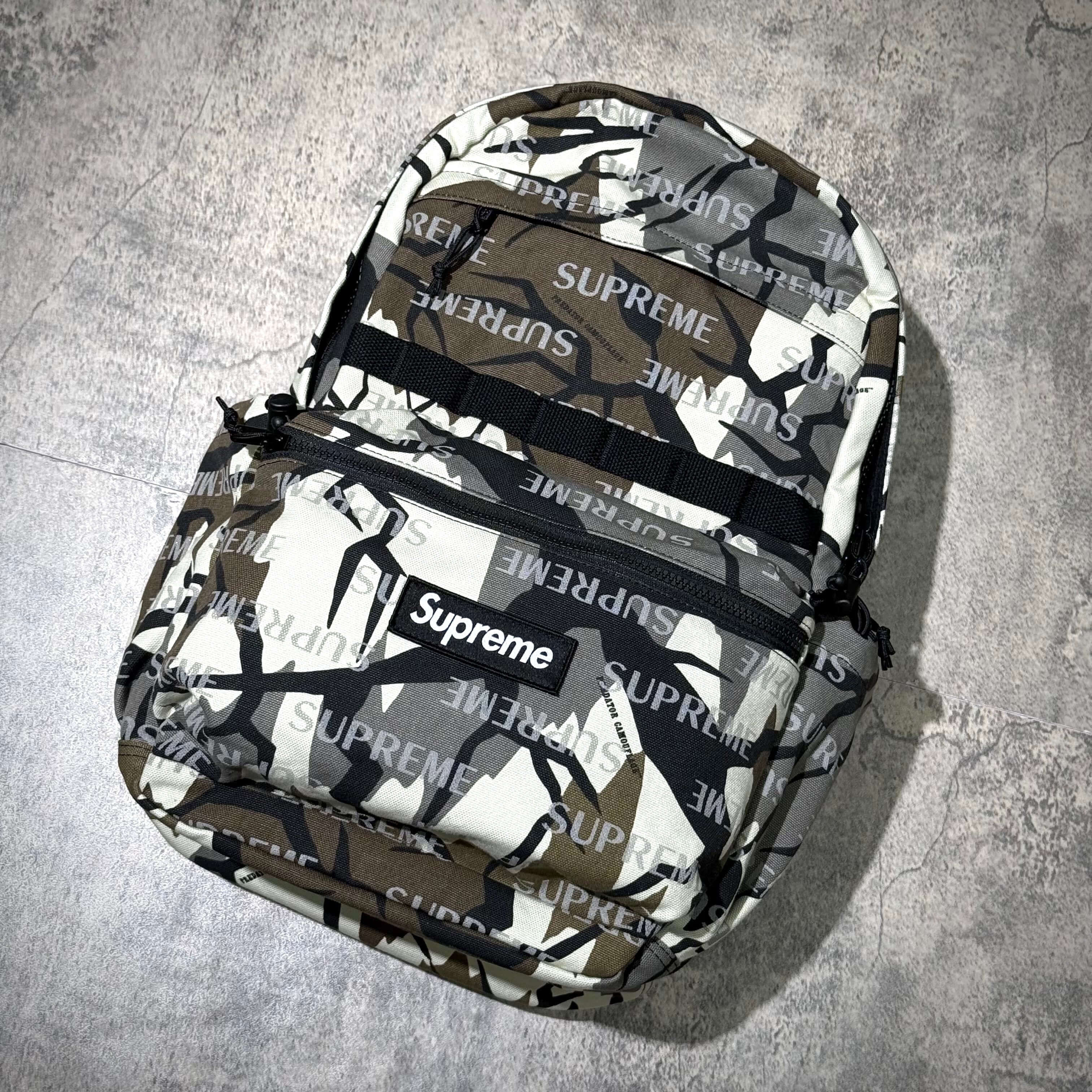 Supreme FW26 Backpack featuring a camouflage pattern and branded design, perfect for streetwear enthusiasts.