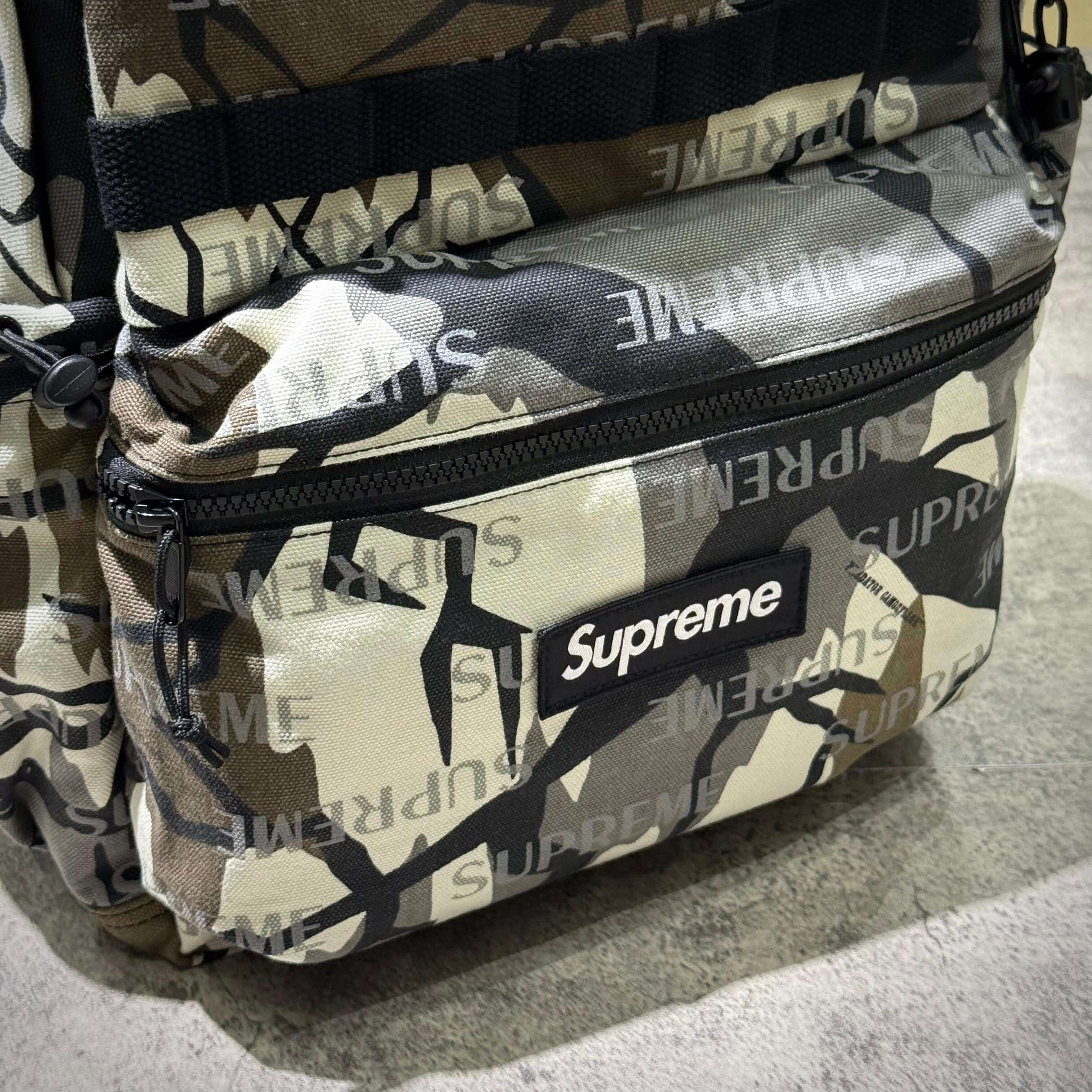 Supreme FW26 Backpack featuring a camo design with the Supreme logo prominently displayed.