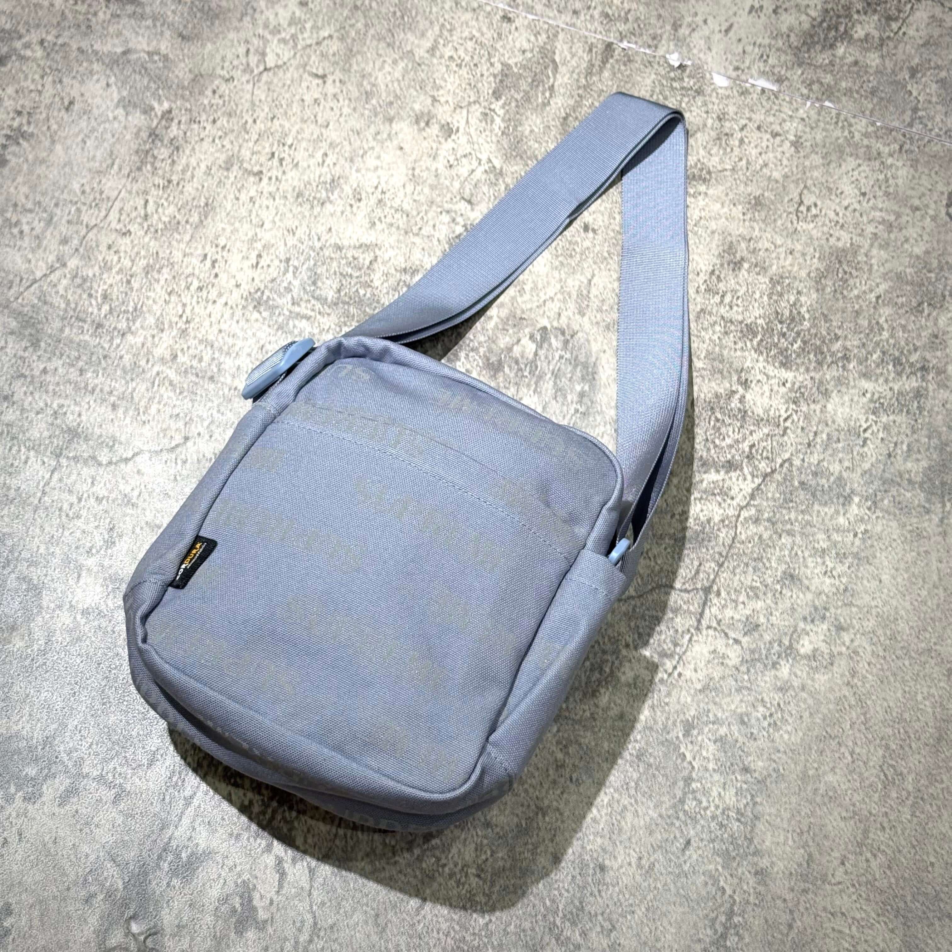Supreme FW26 Shoulder Bag in a muted gray color with a simple design and adjustable strap.