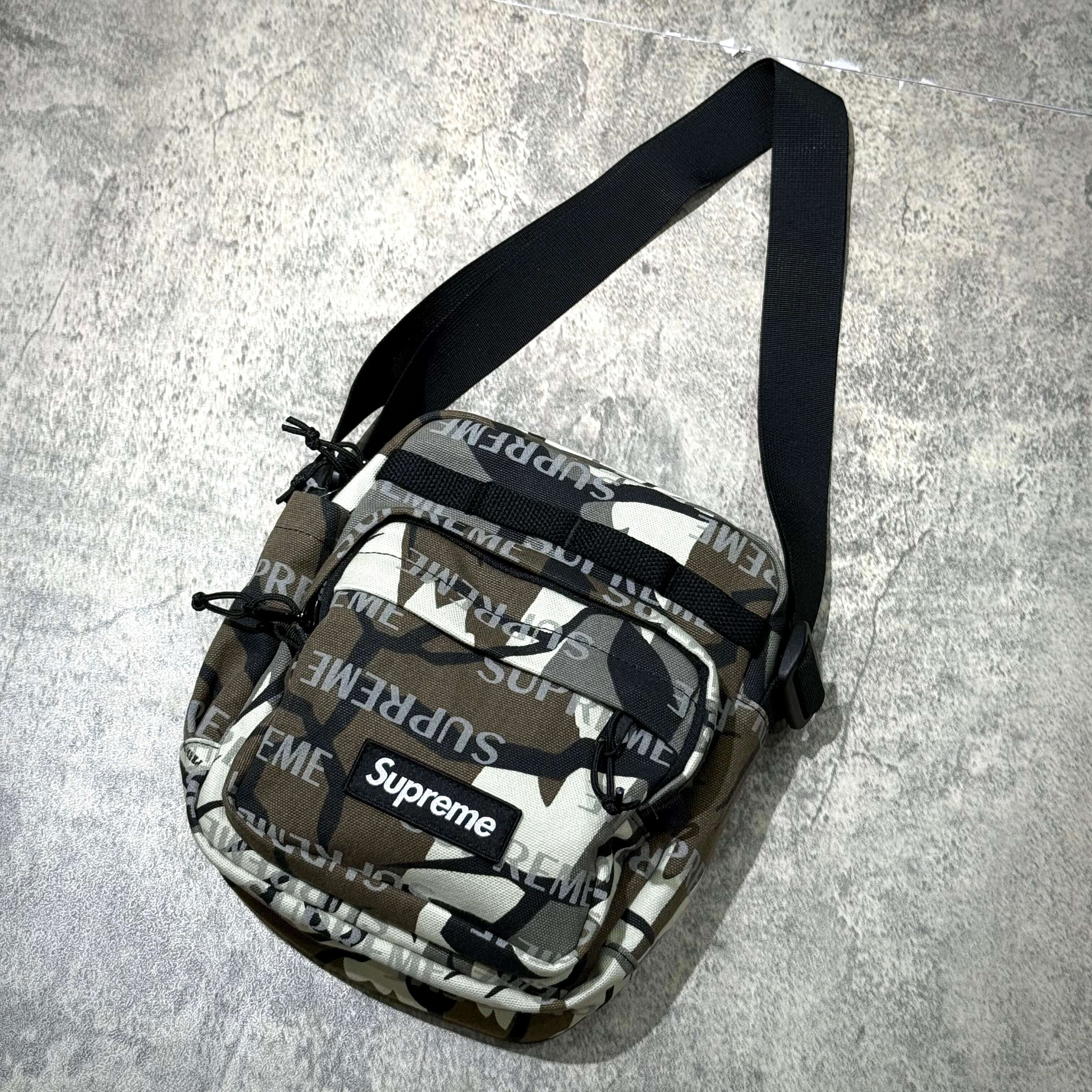 Supreme FW26 Shoulder Bag in camo print with adjustable strap and logo on front, showcasing streetwear style.