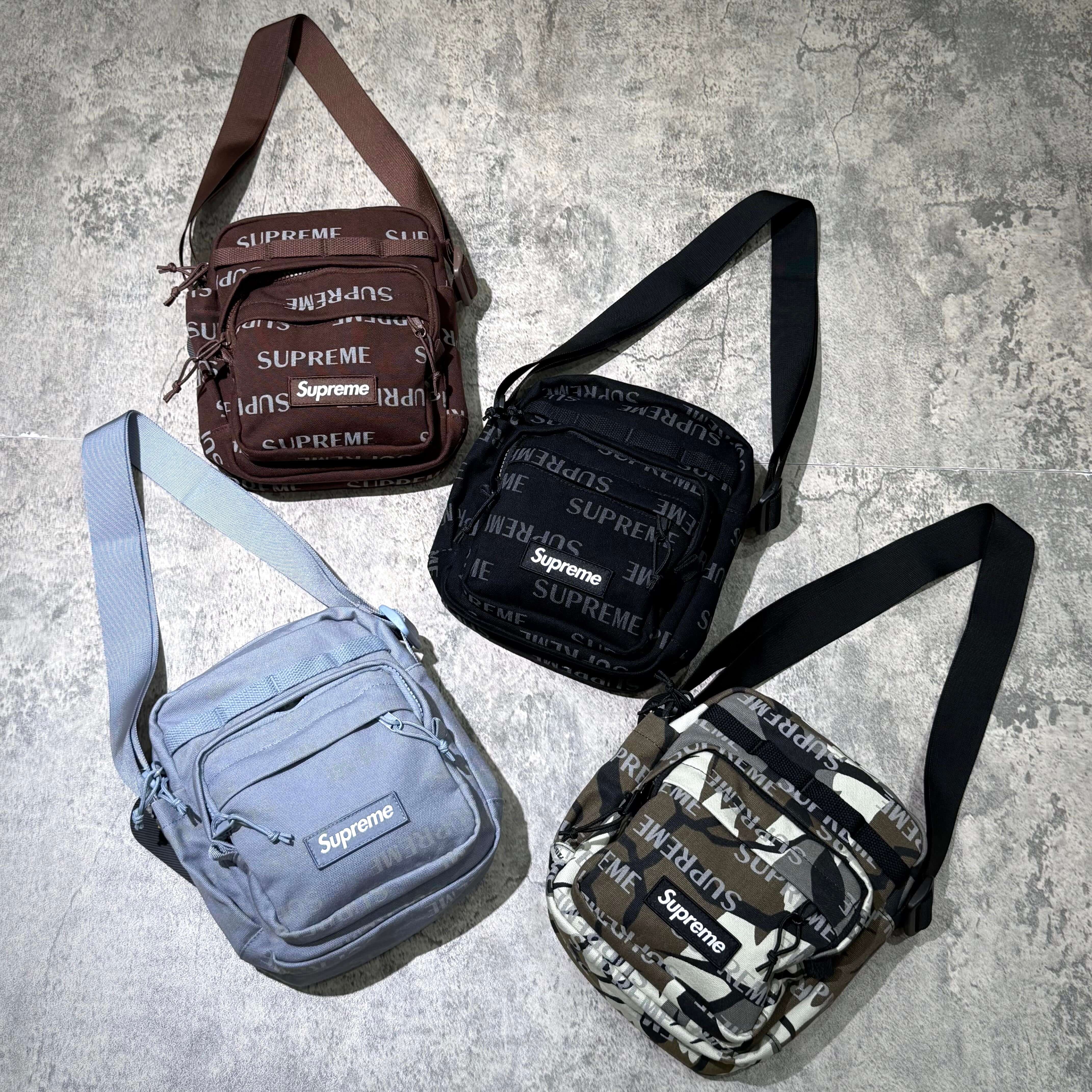 Four Supreme FW26 Shoulder Bags displayed in brown, black, gray, and camouflage patterns on a textured surface.
