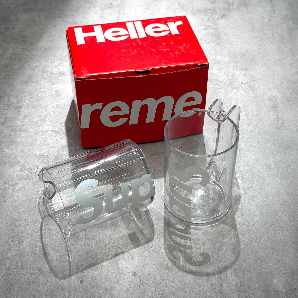 Supreme Heller Mugs Set of 2 - Clear displayed beside packaging on a gray surface.