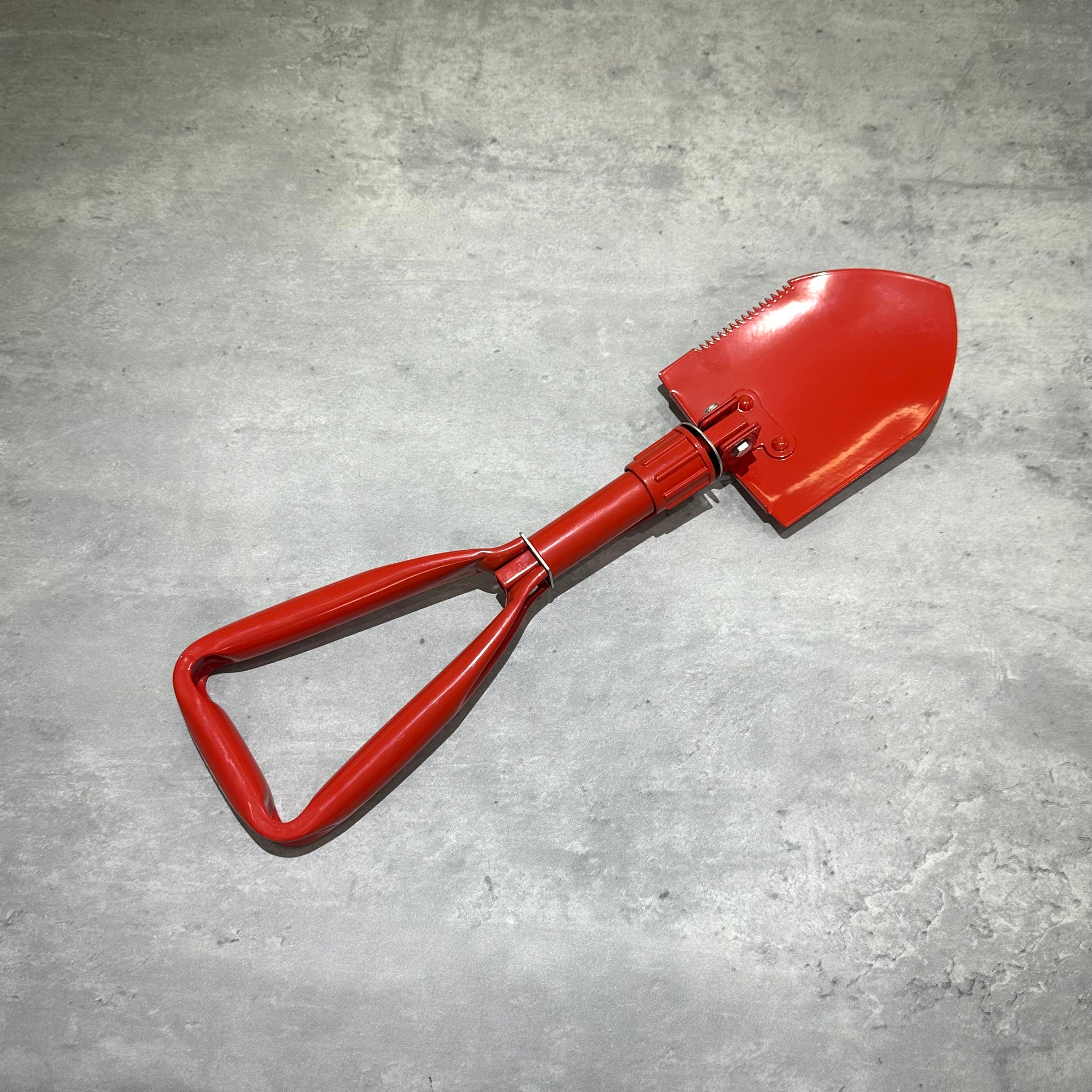 Supreme SOG Collapsible Shovel with a bright red handle and sharp blade, designed for durability and ease of use.