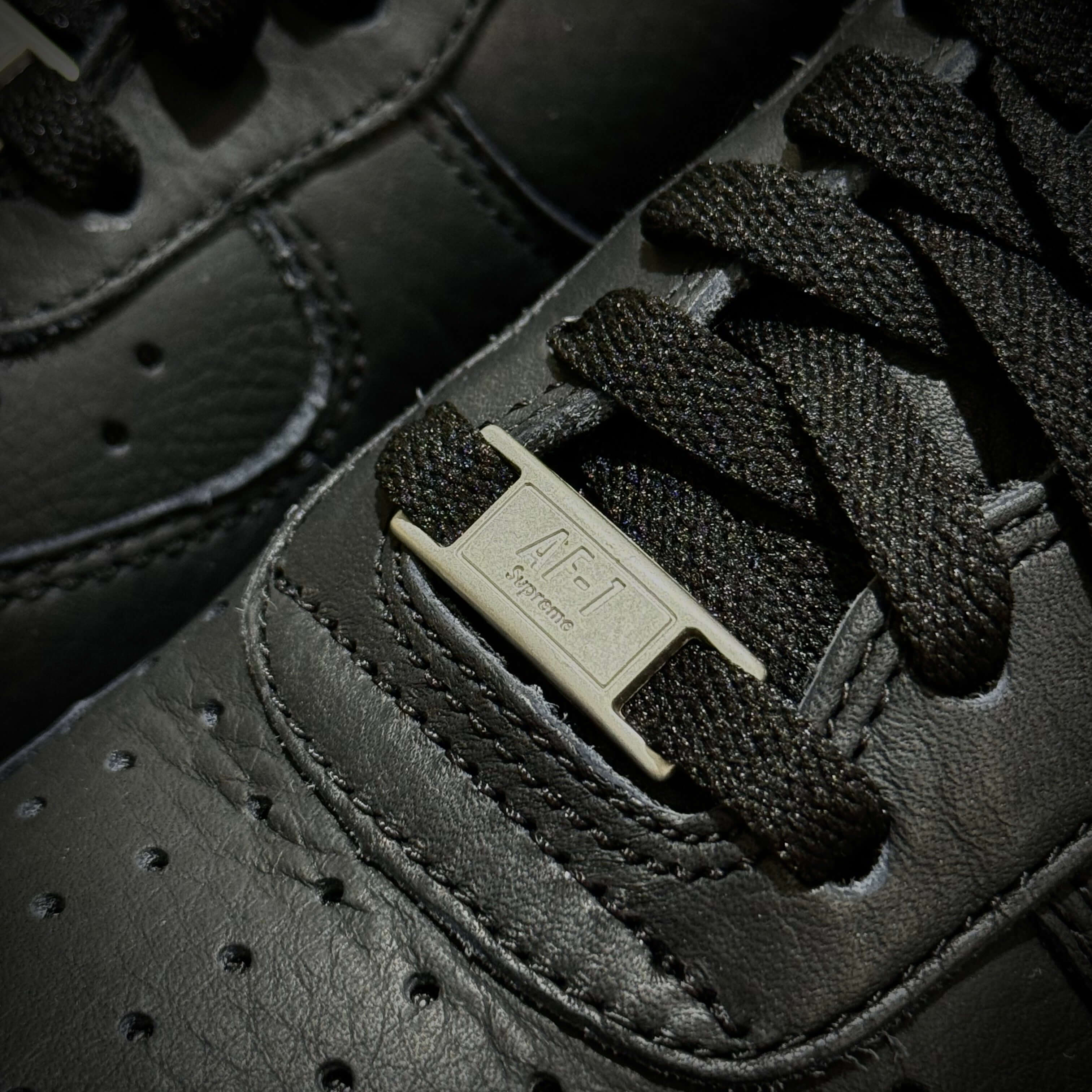 Close-up of the laces and tag of the Supreme x Comme des Garçons x Nike Split Logo Air Force 1 Low sneakers.