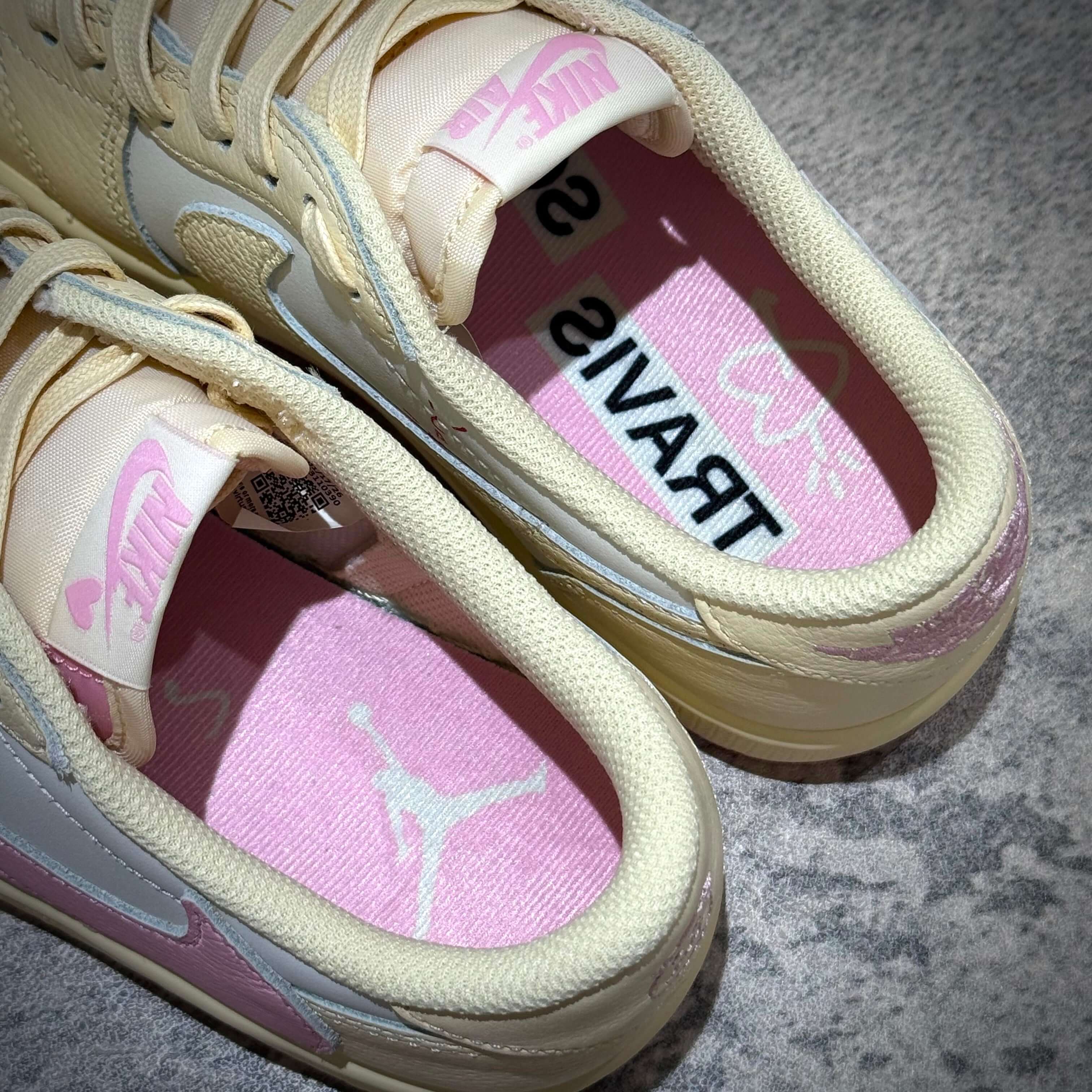 Travis Scott × Nike Air Jordan 1 Retro Low SP - Shy Pink sneakers showing inner soles with Jordan and Travis branding.